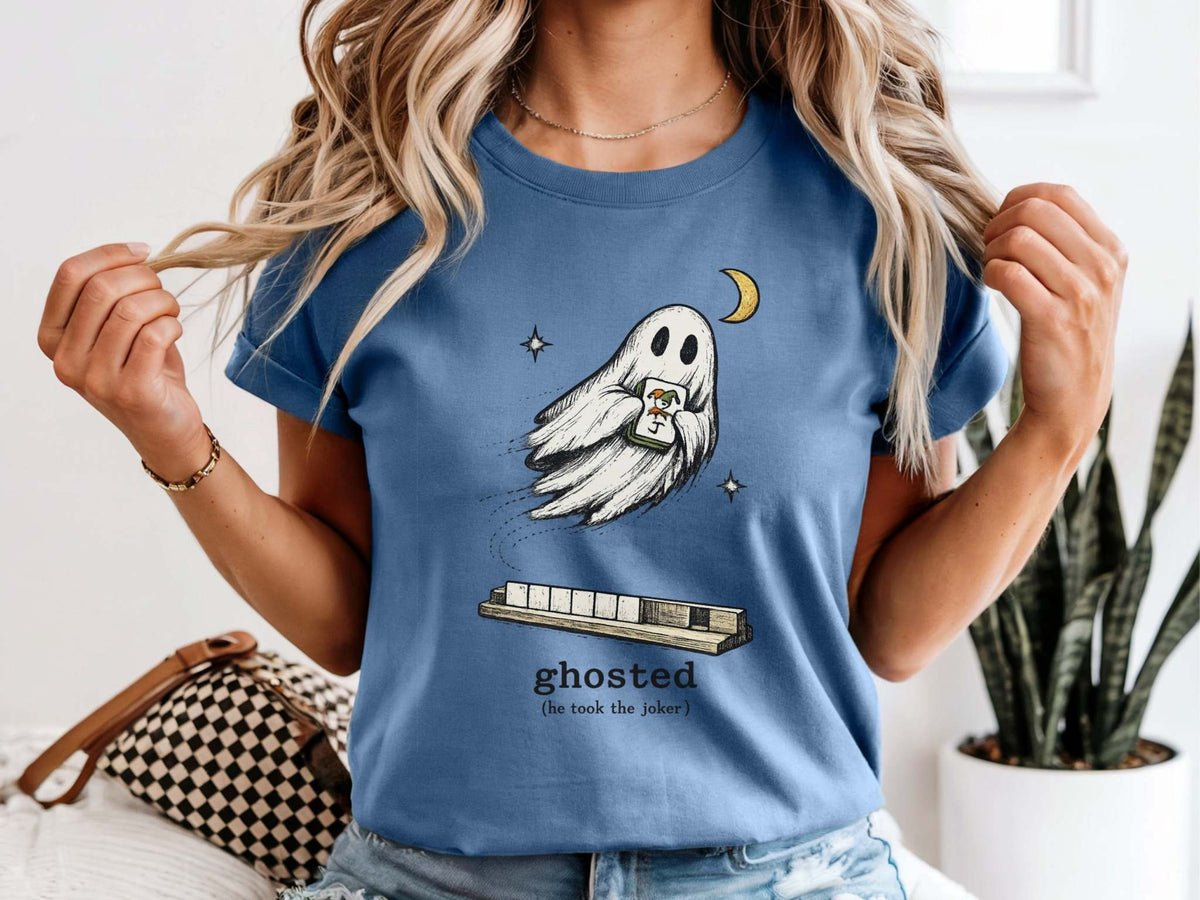 Model wearing a blue jean mahjong T-shirt with a ghost holding a joker tile above a tile rack and “ghosted (he took the joker)” lettering.