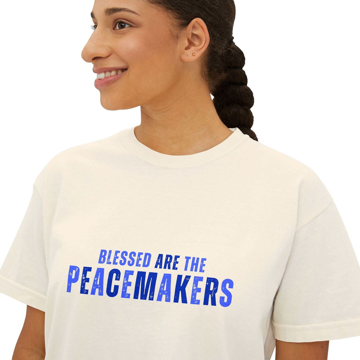 Woman wearing a white Tee Blessed be the Peacemakers women's boxy shirt with blue text promoting peace and harmony