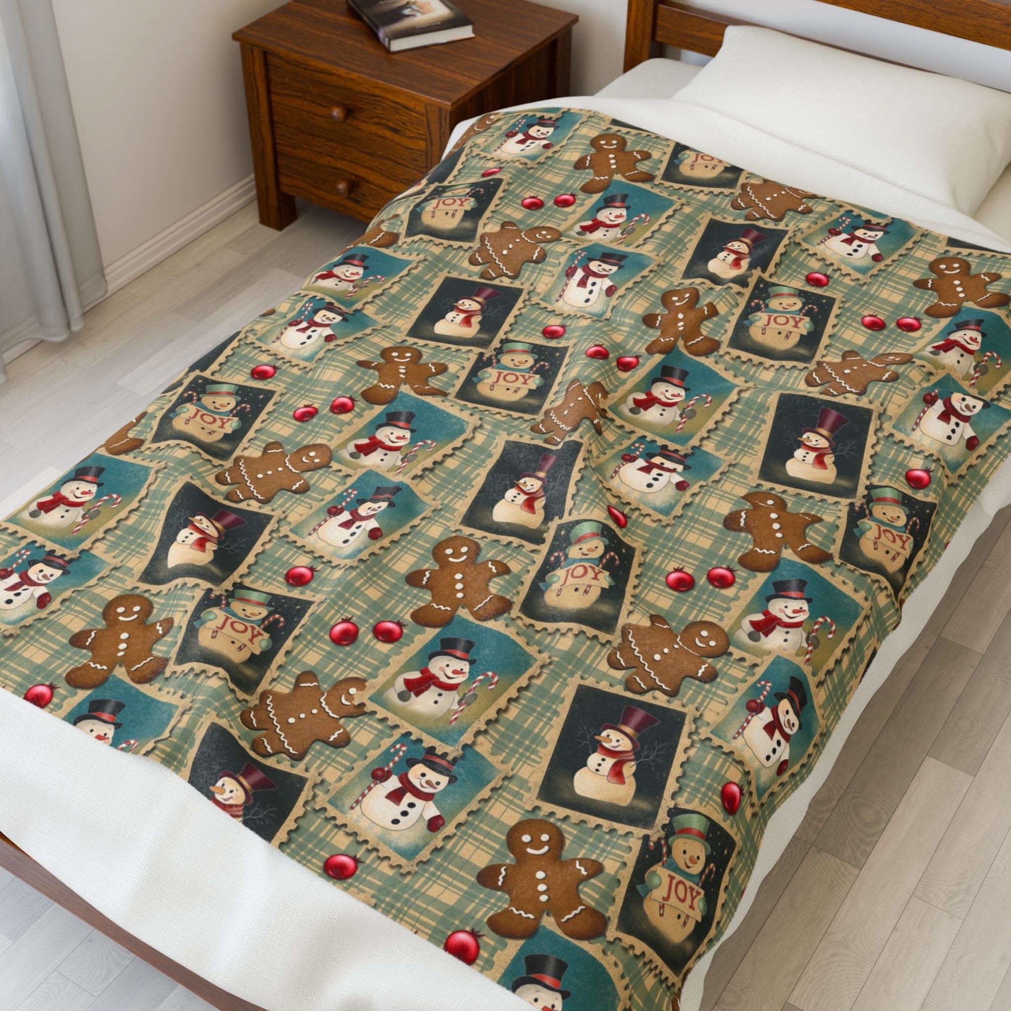 Plush blanket with retro Christmas watercolor design featuring snowmen, gingerbread men, and festive "JOY" frames on a cozy bed setting