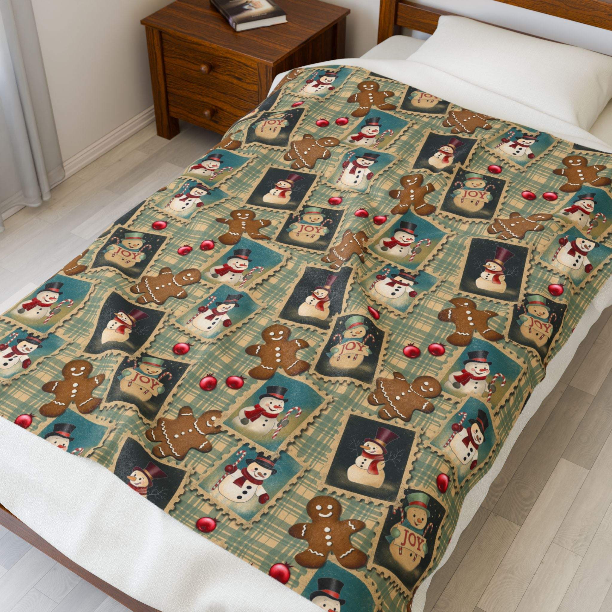 Plush blanket with retro Christmas watercolor design featuring snowmen, gingerbread men, and festive "JOY" frames on a cozy bed setting