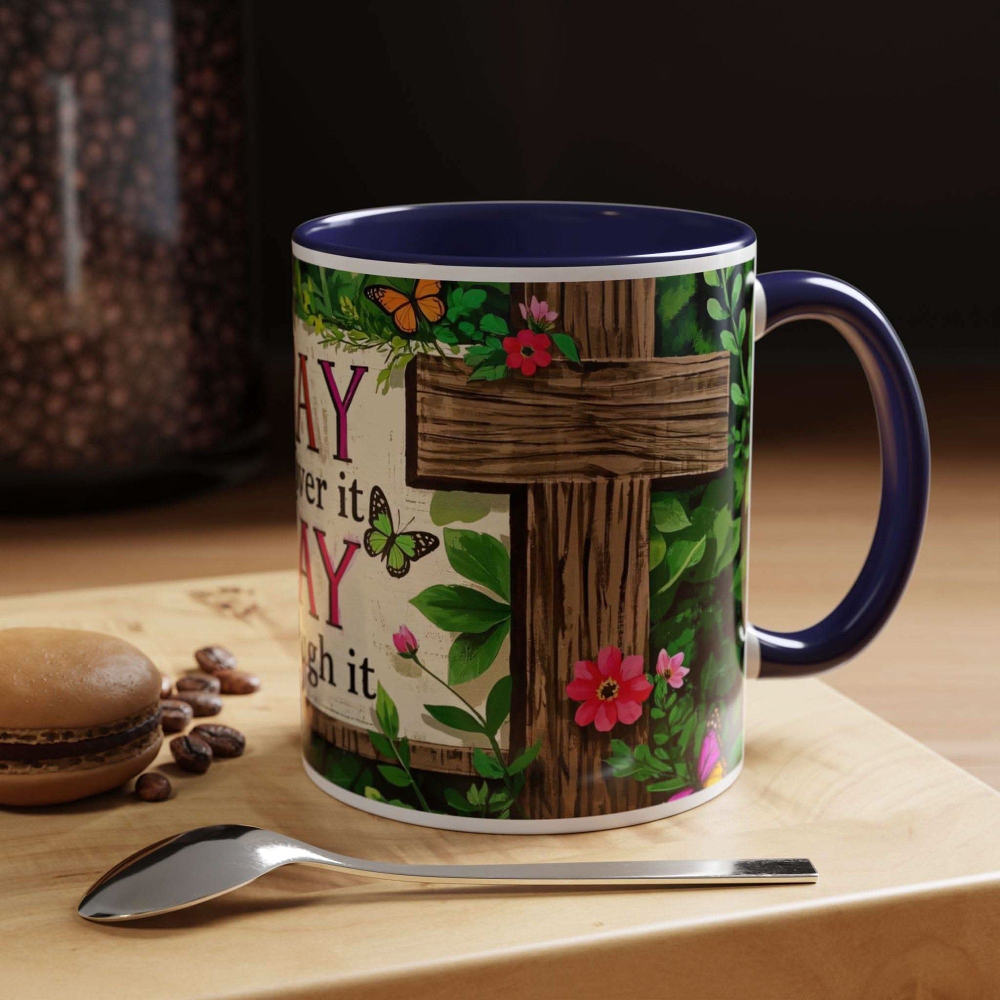 Decorative mug with floral and butterfly design on a wooden surface with coffee beans and a spoon.