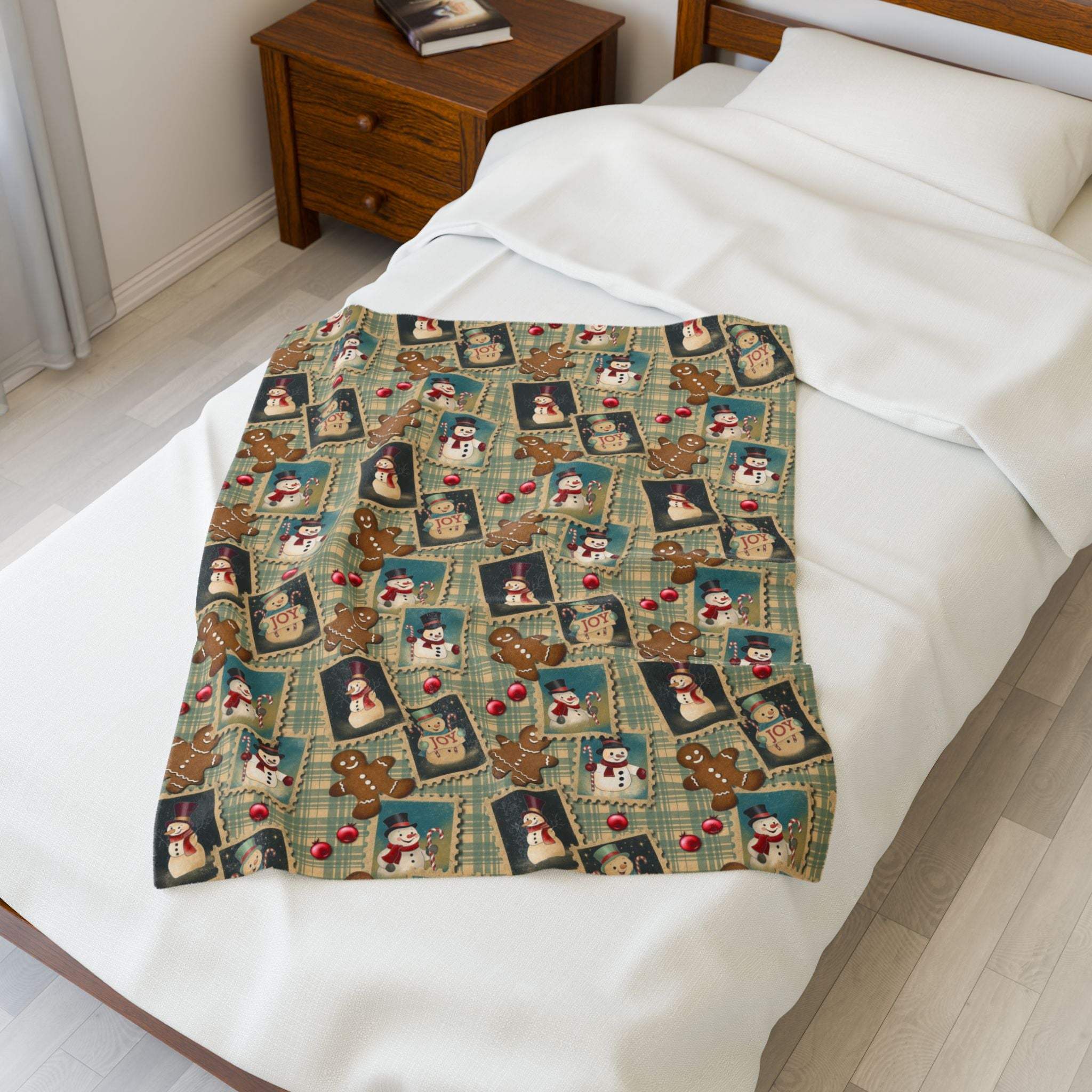Plush blanket with retro Christmas watercolor design featuring snowmen, gingerbread men, and holiday stamps on a bed