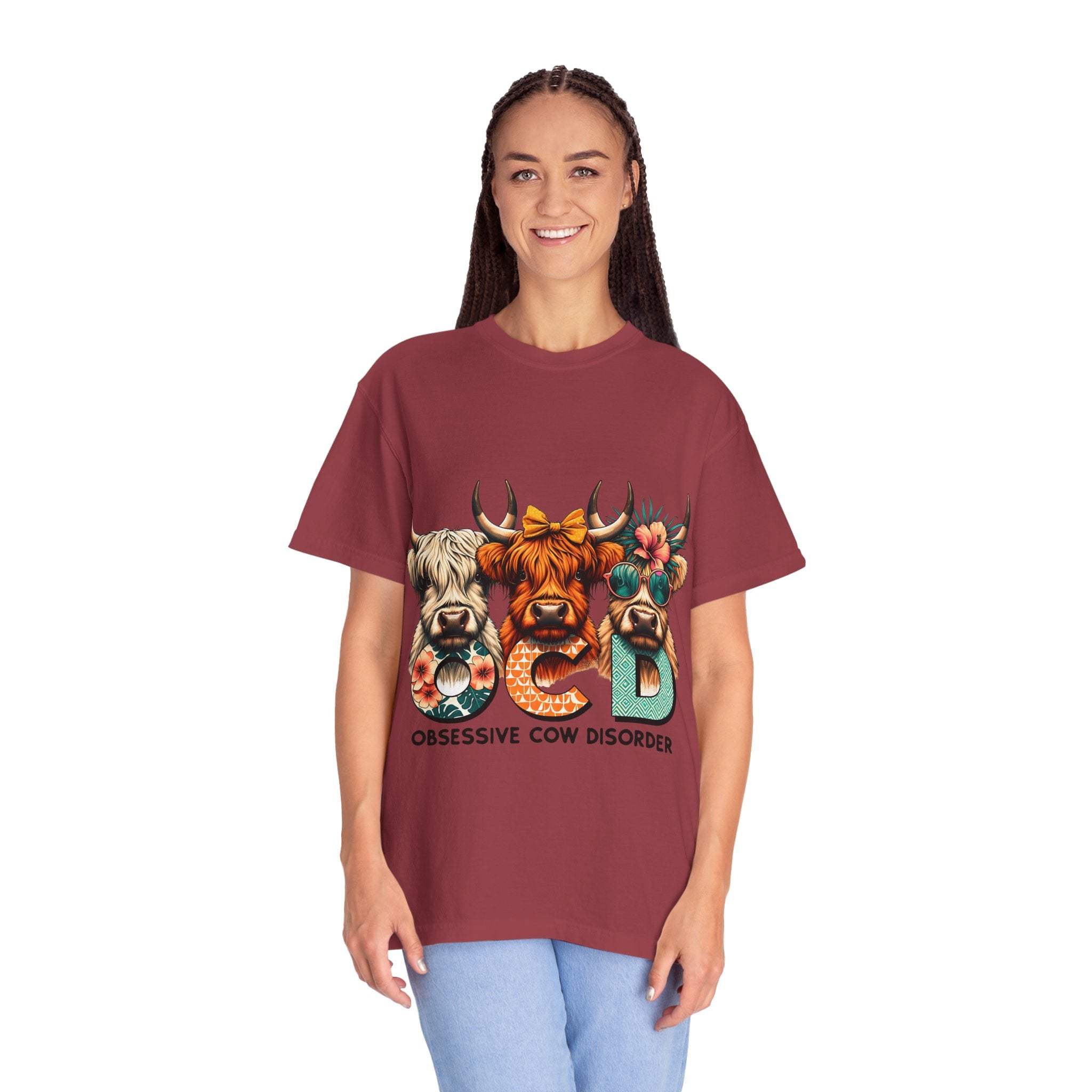 Woman wearing Funny OCD Obsessive Cow Disorder graphic T-shirt with colorful cow illustrations on maroon garment-dyed fabric
