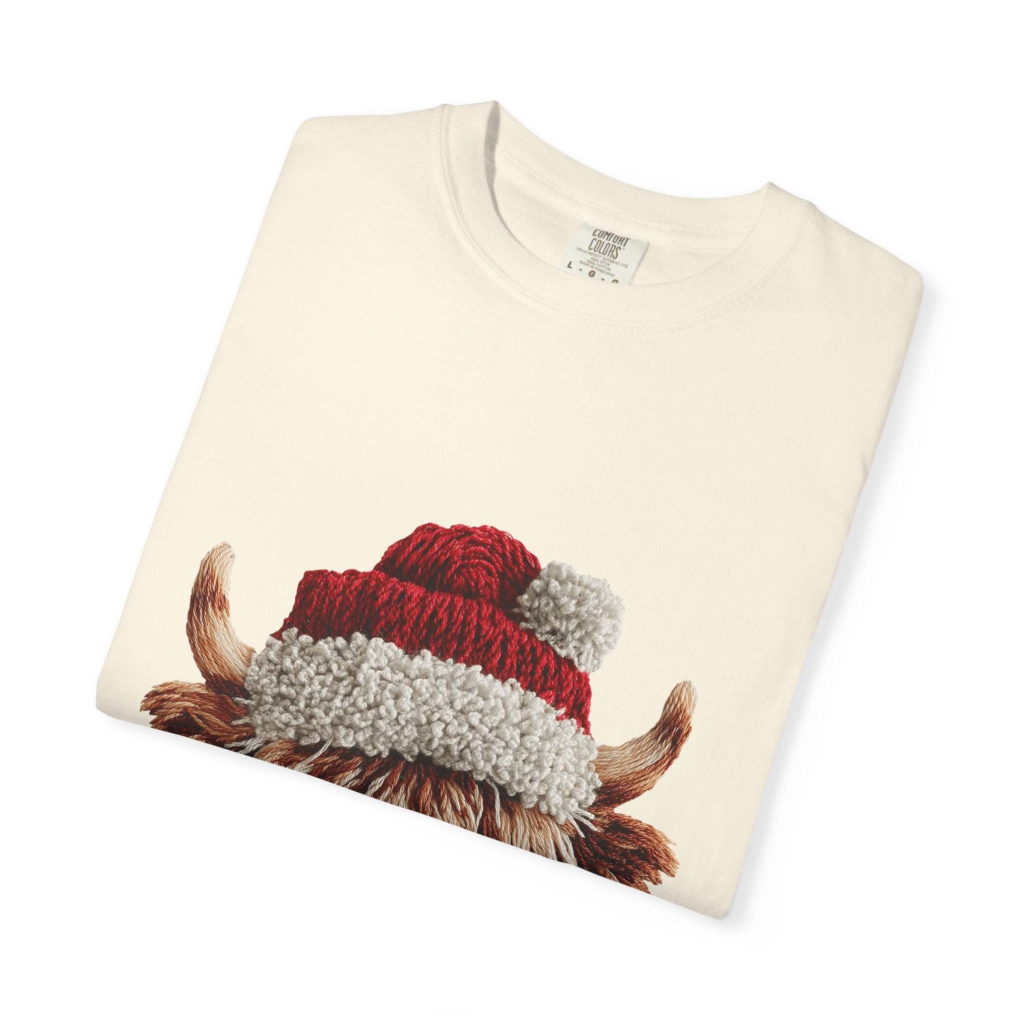 Cream T-shirt with faux crochet yarn highland cow wearing Santa hat print