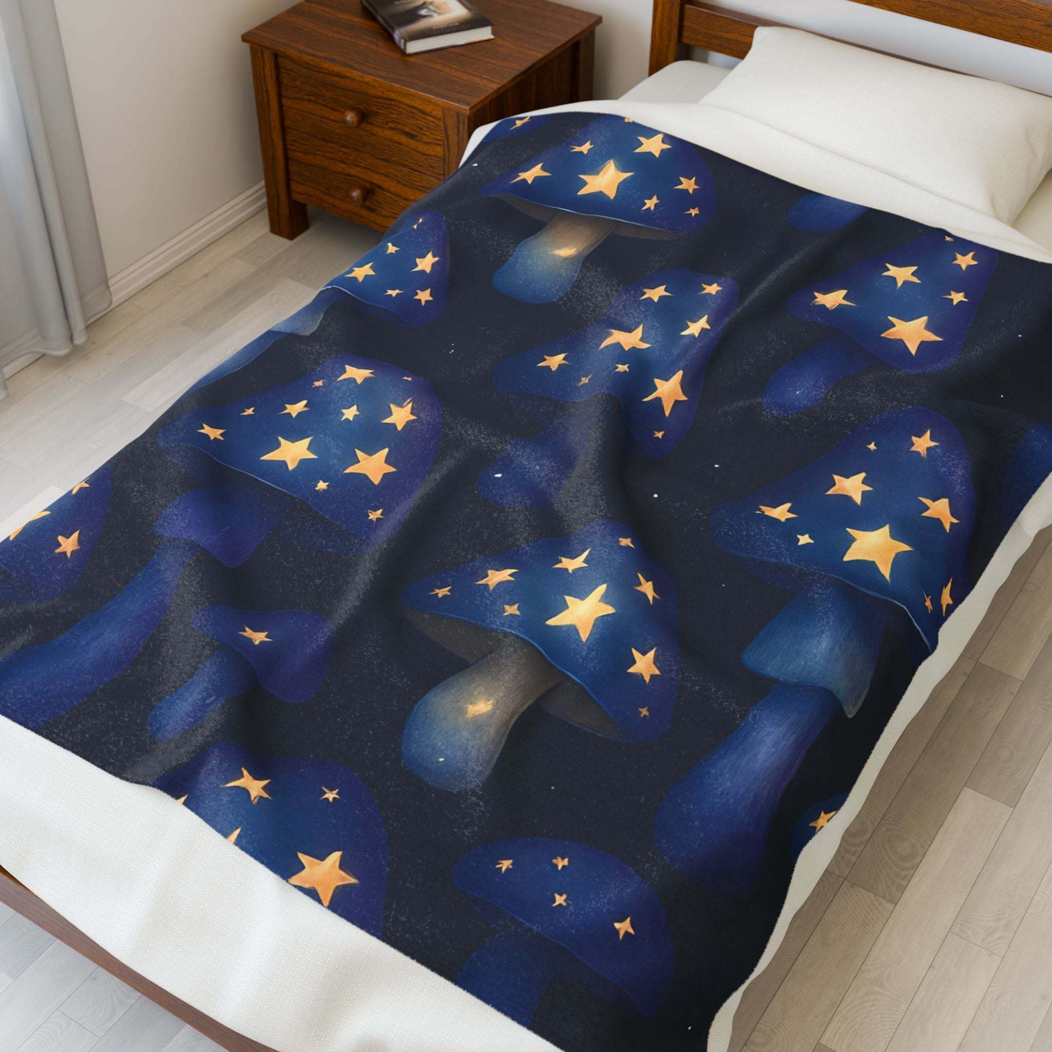 Velveteen plush blanket with whimsical blue mushrooms and glowing yellow stars on bed
