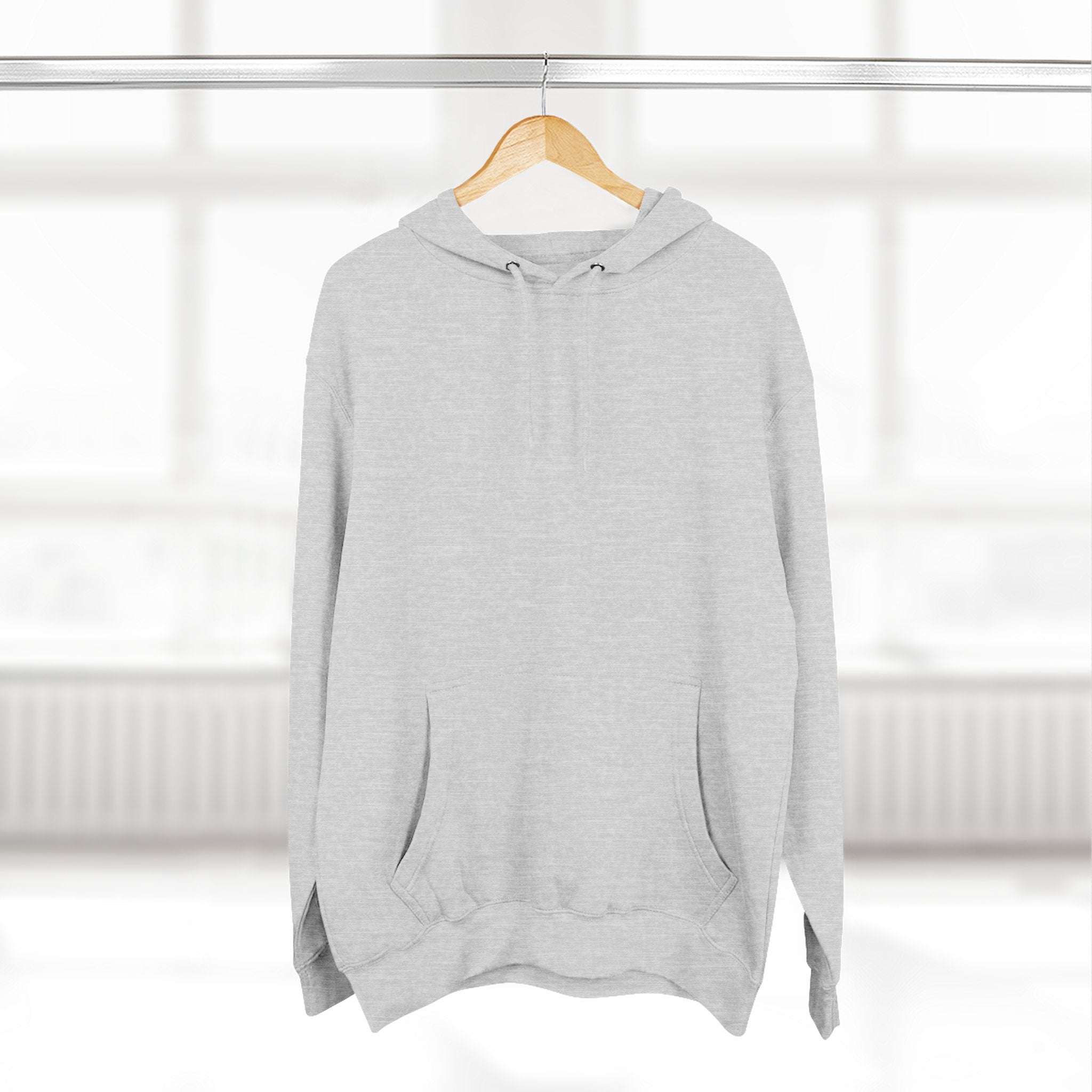 Light gray fleece hoodie with adjustable hood and kangaroo pocket hanging on wooden hanger in bright room