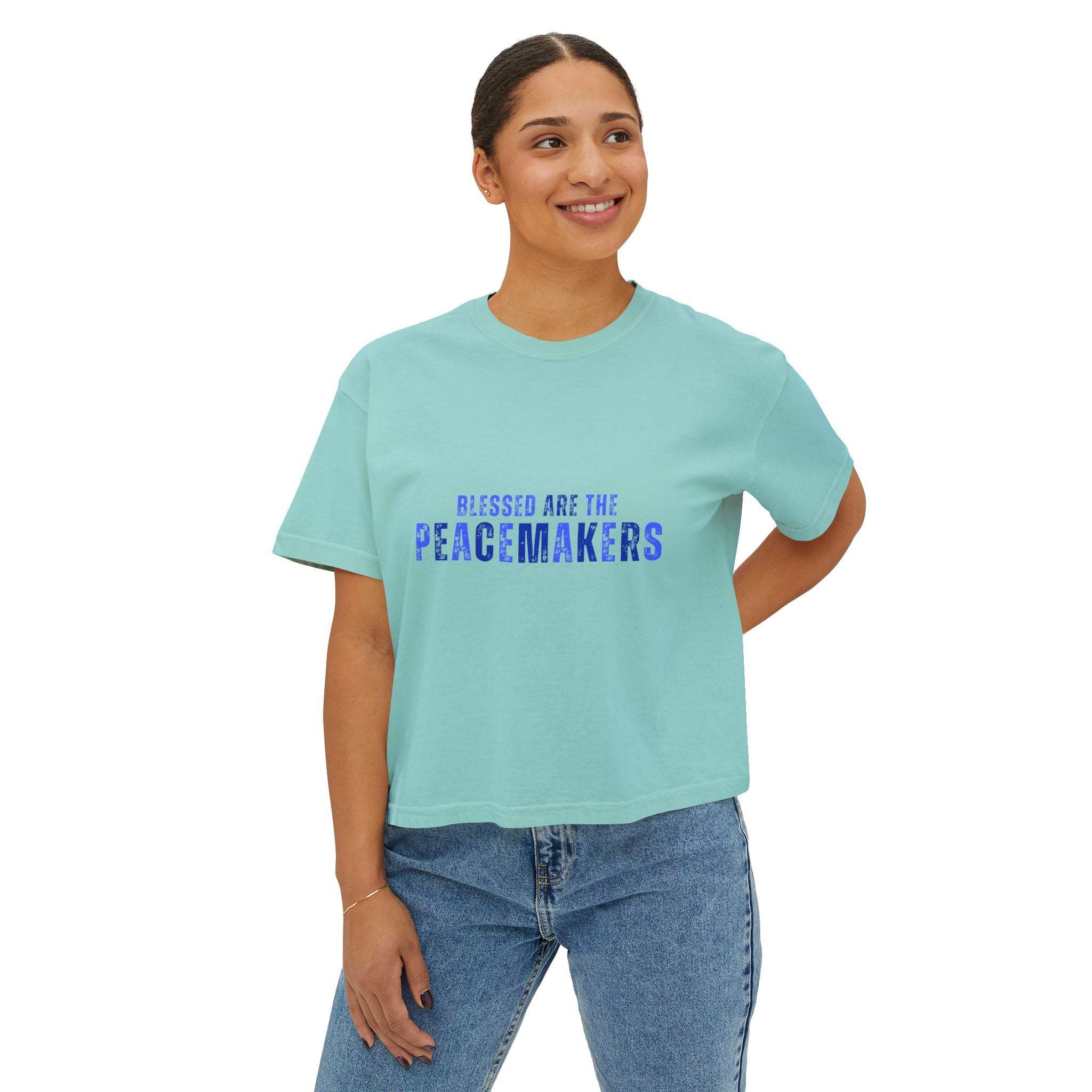 Woman wearing a light blue Tee Blessed be the Peacemakers boxy shirt with purple text and casual jeans