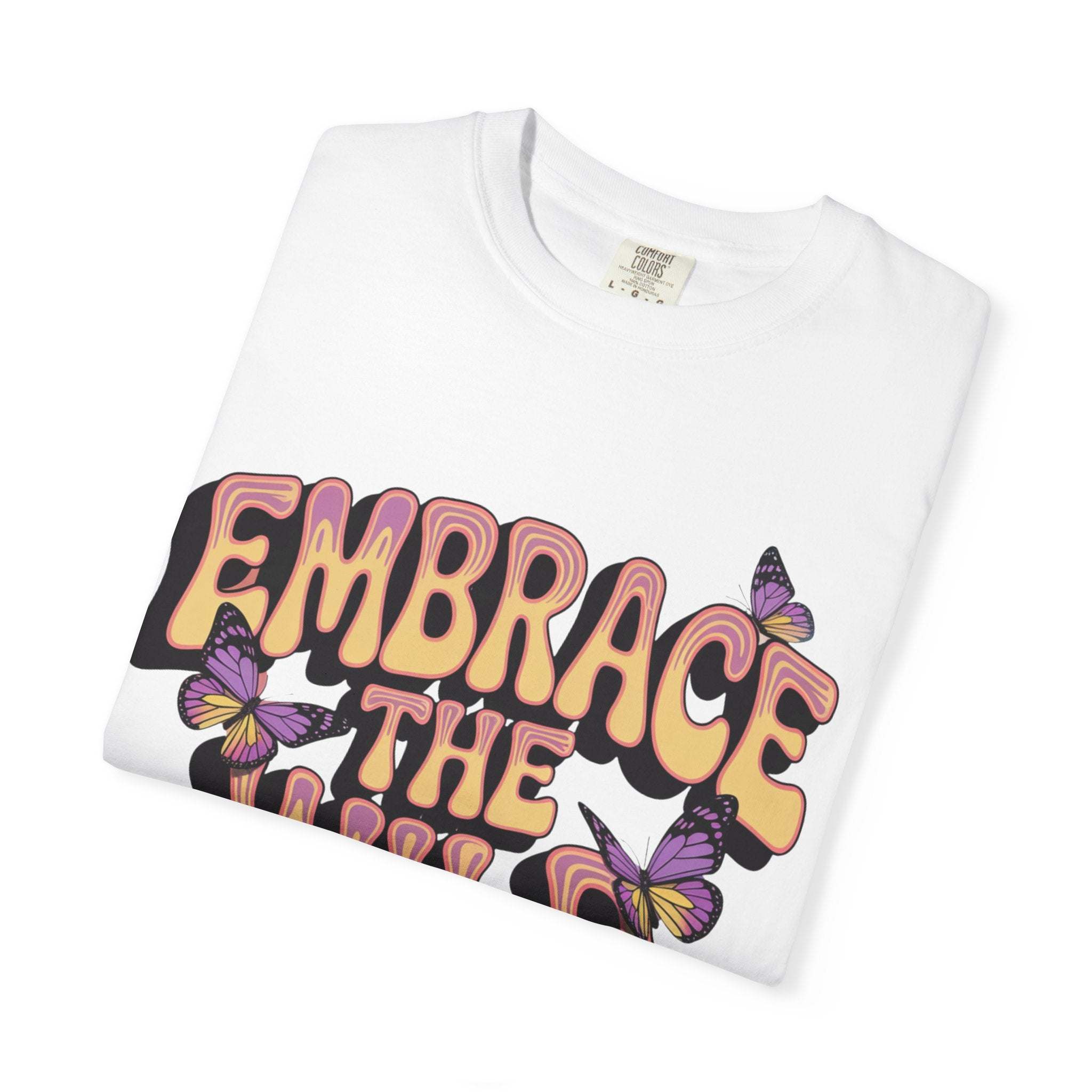 Folded white garment-dyed T-shirt with "Embrace the Wild Side" print and colorful butterfly design
