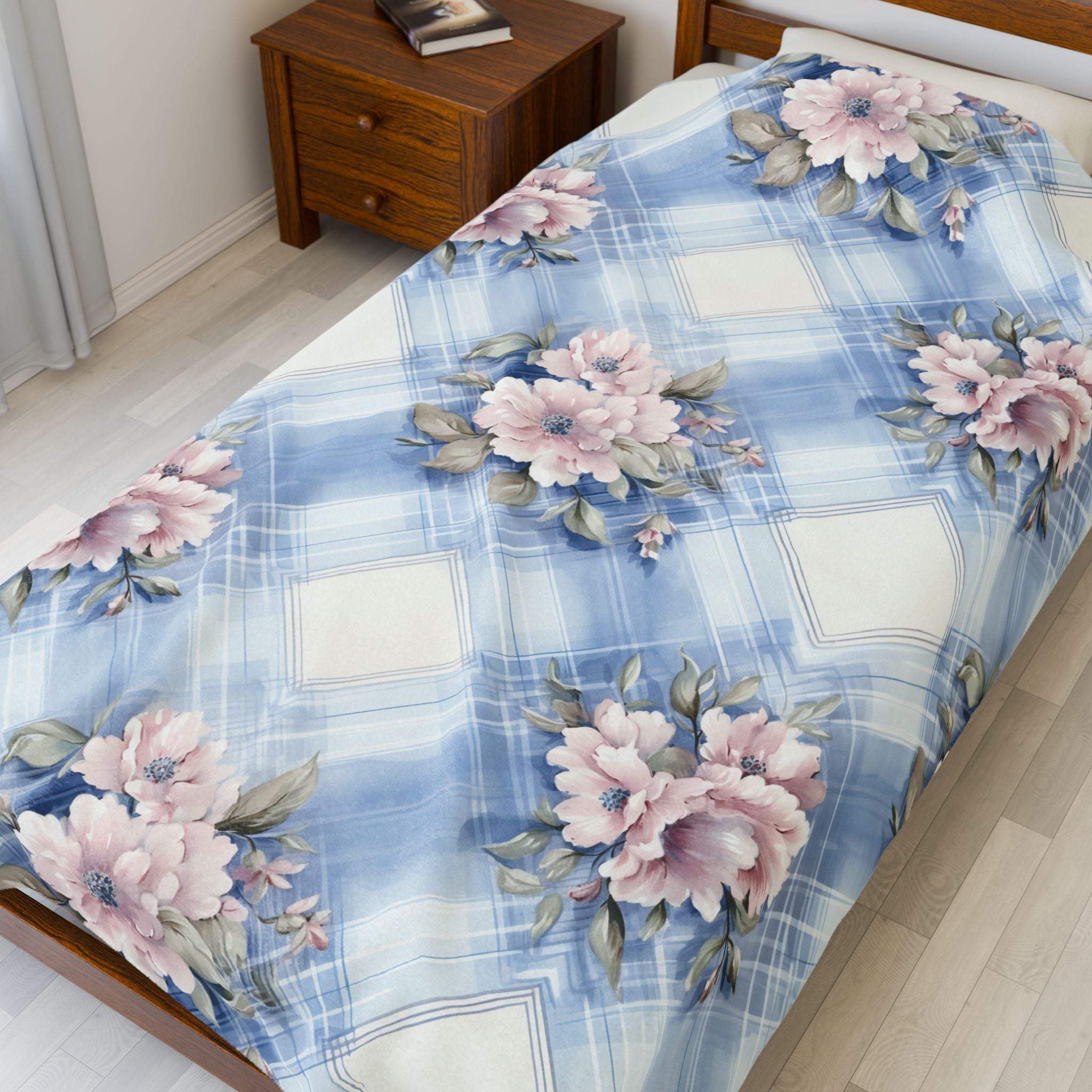 Soft velveteen plush blanket with pastel blue and pink floral design on bed