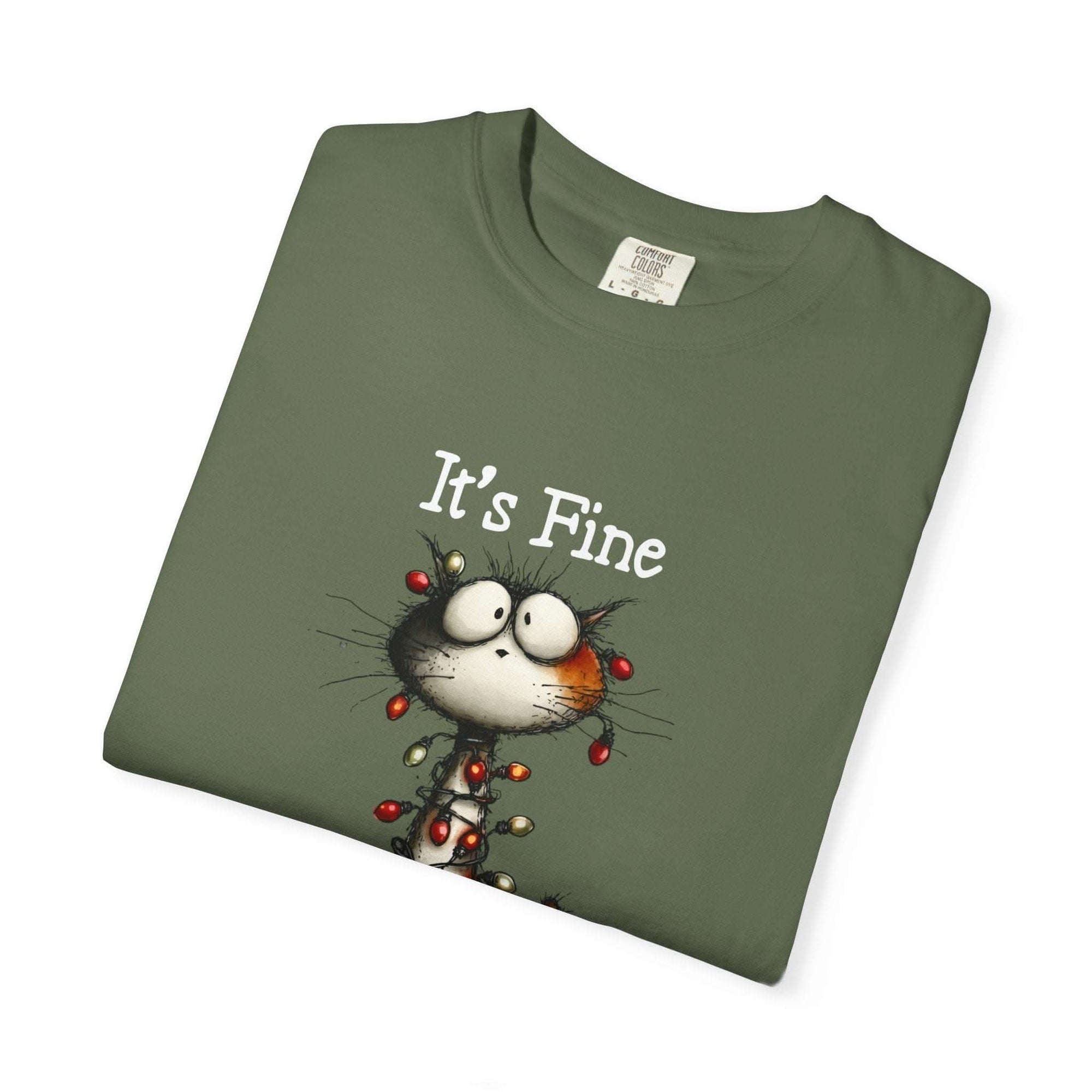 Folded green t-shirt with a cartoon cat and 'It's Fine' text on a white background