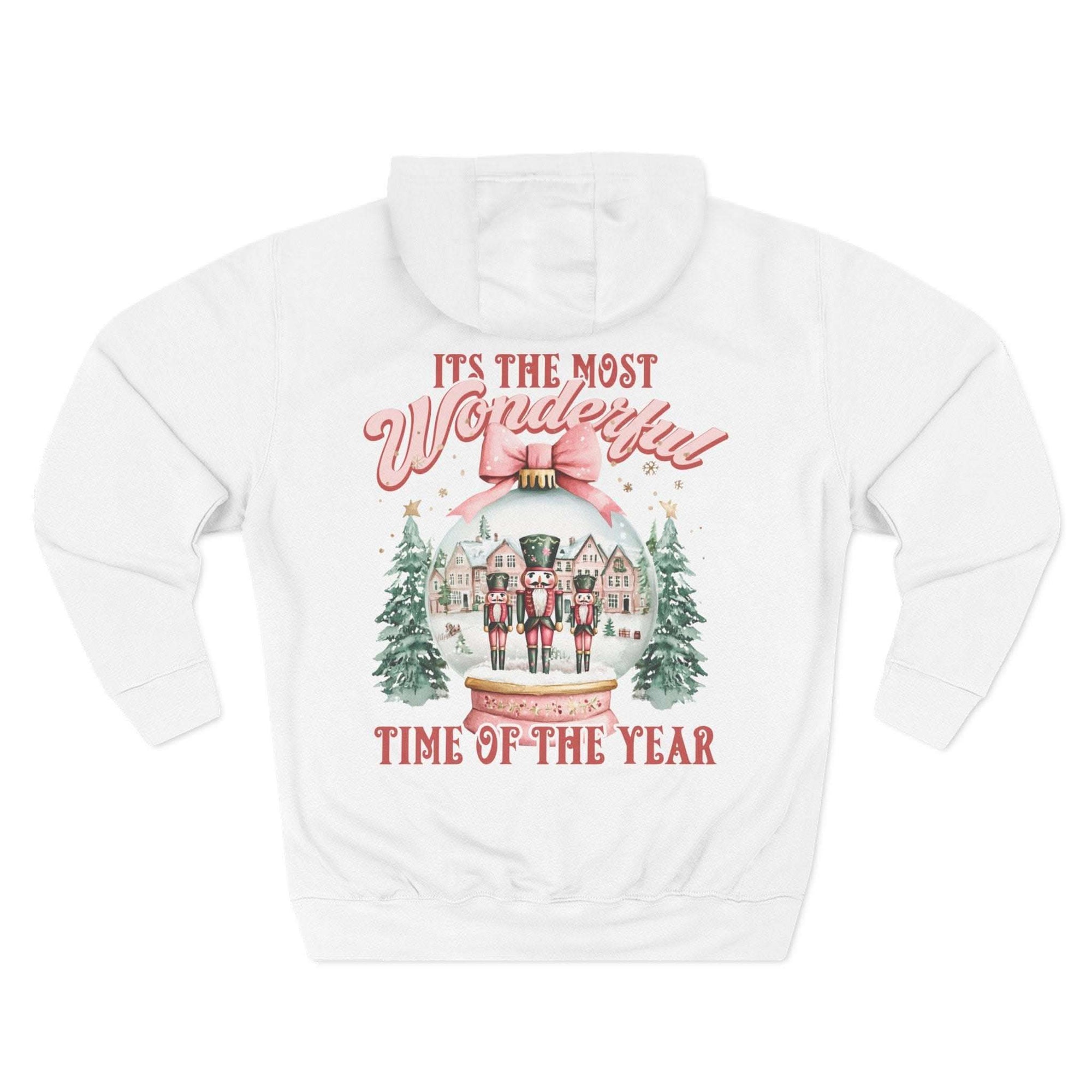 White fleece hoodie with pink snow globe and nutcracker holiday design, cozy winter comfort
