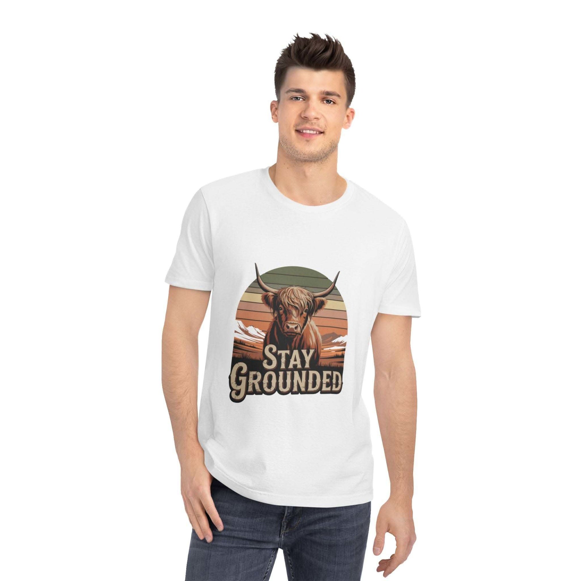Man wearing a white t-shirt with a graphic of a cow and 'Stay Grounded' text on a white background