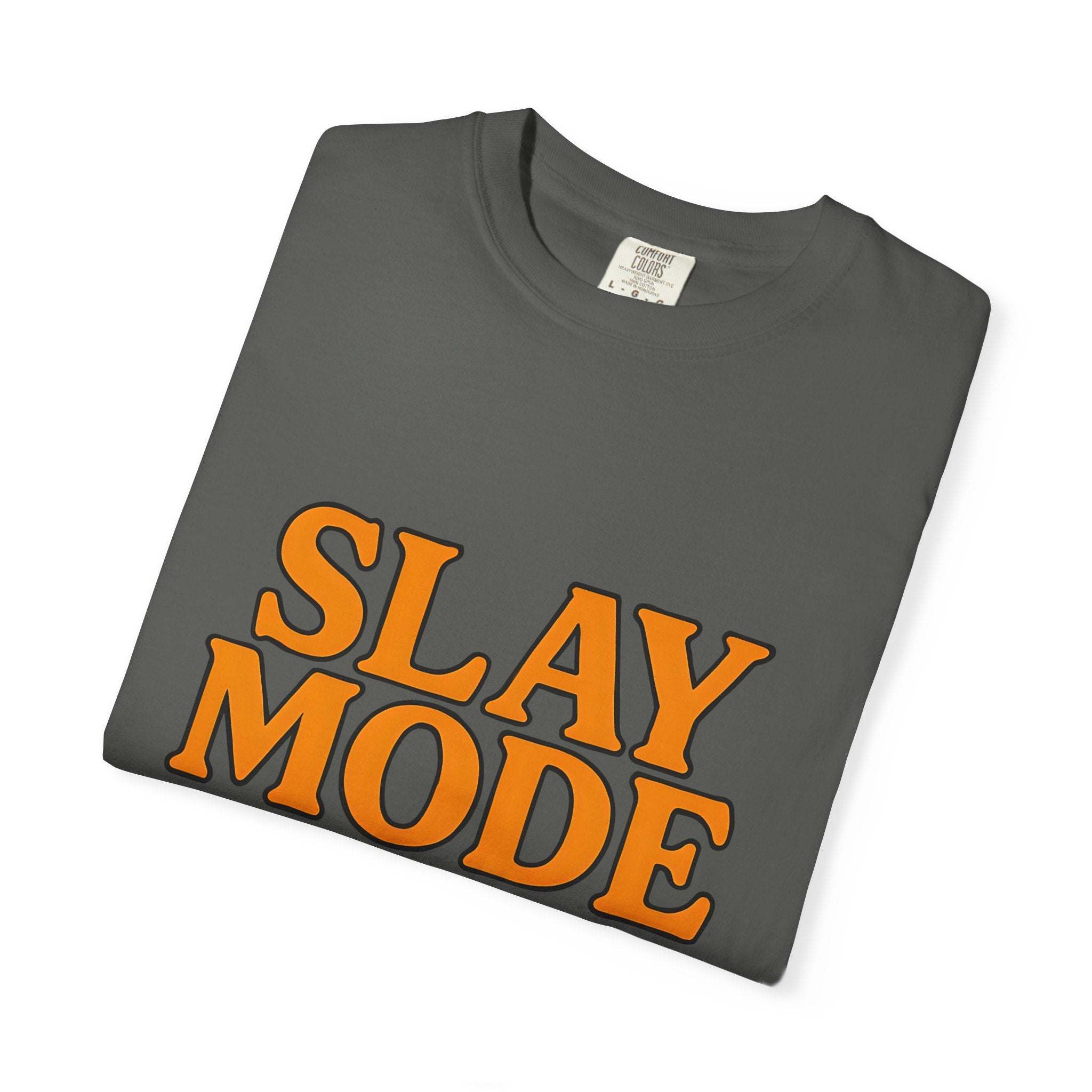Garment-dyed tee folded with orange "SLAY MODE" text on dark fabric for casual and motivational wear