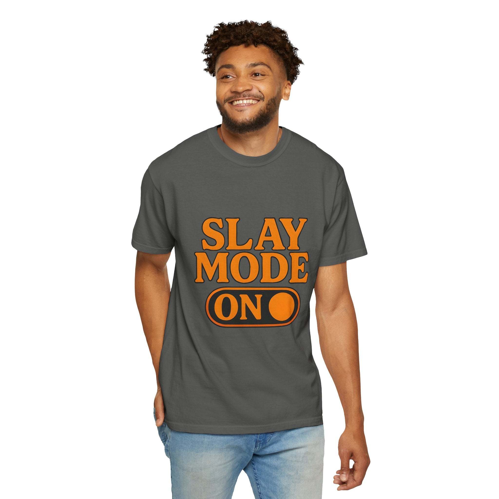 Man wearing garment-dyed gray Slay Mode On tee with orange print and blue jeans