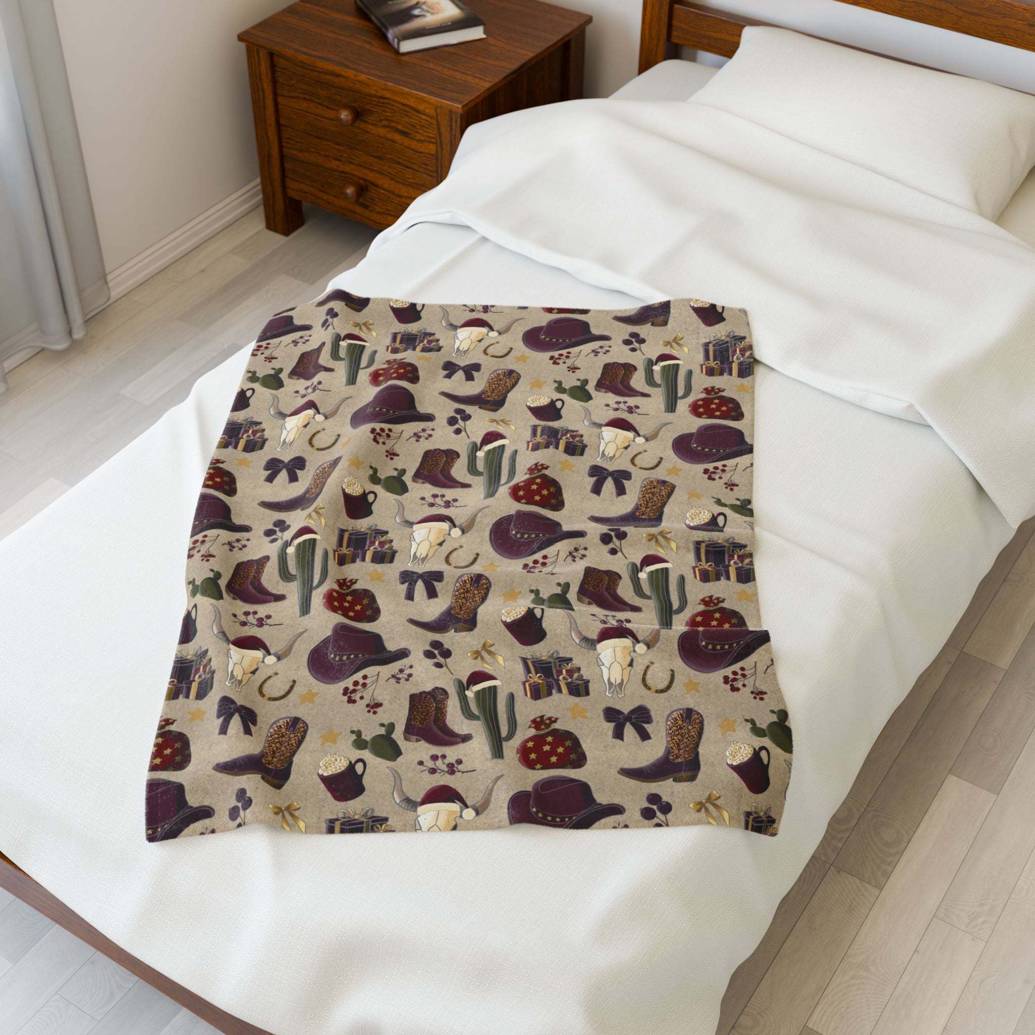 Cozy plush blanket with cowboy Christmas design featuring hats, boots, and cacti on bed