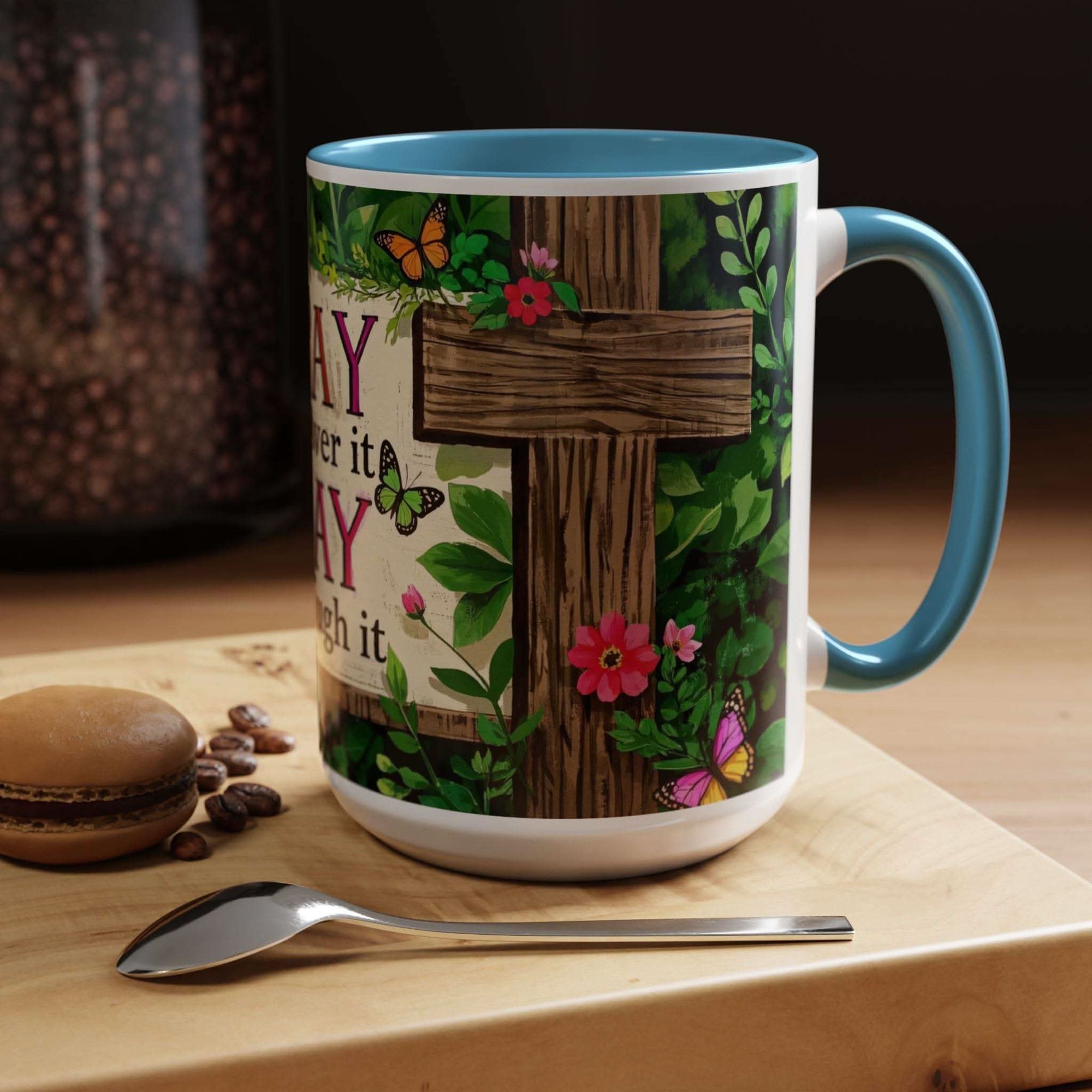 Mug with cross and floral design on a wooden surface with coffee beans and a cookie.