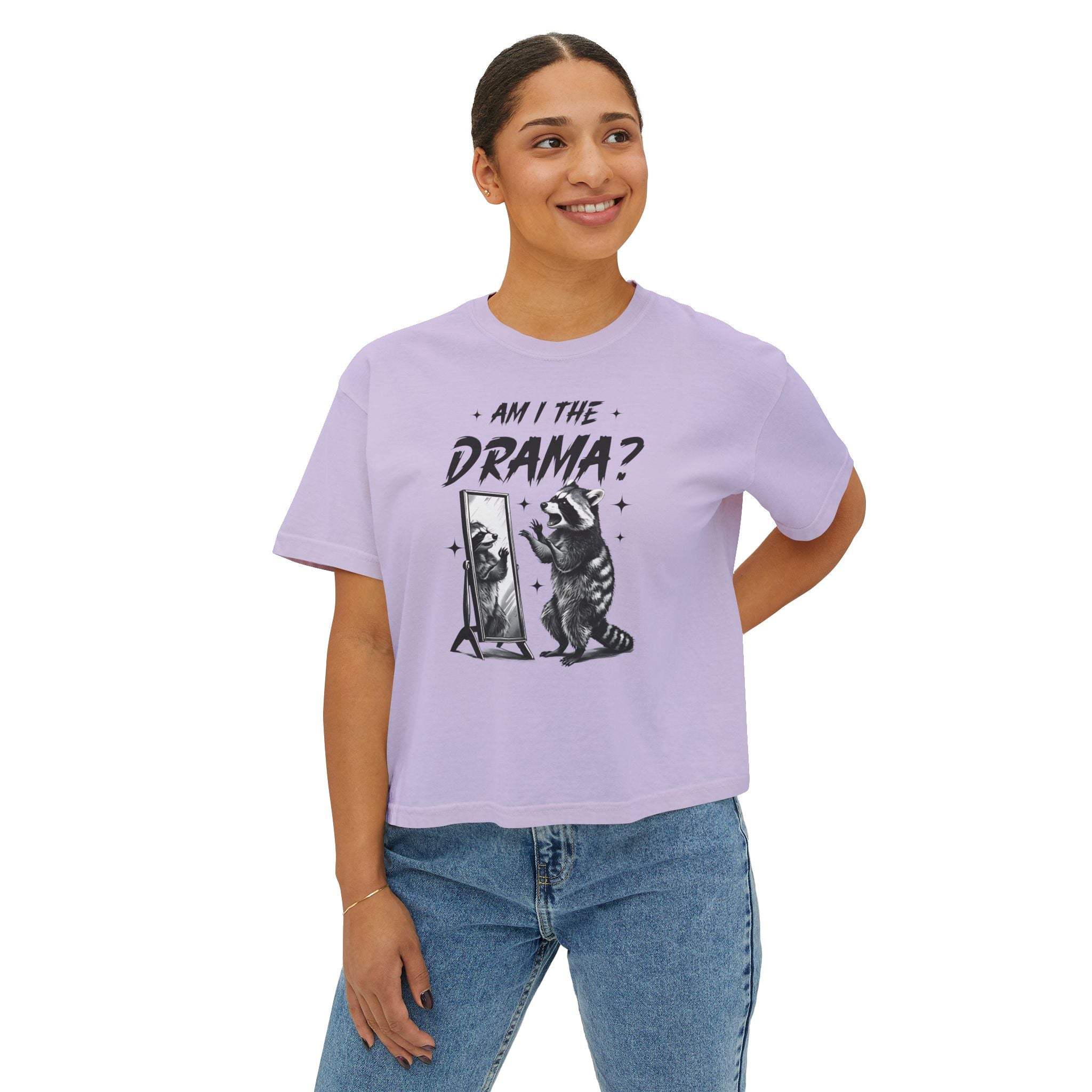 Woman wearing lavender boxy tee with "Am I The Drama?" raccoon graphic and jeans