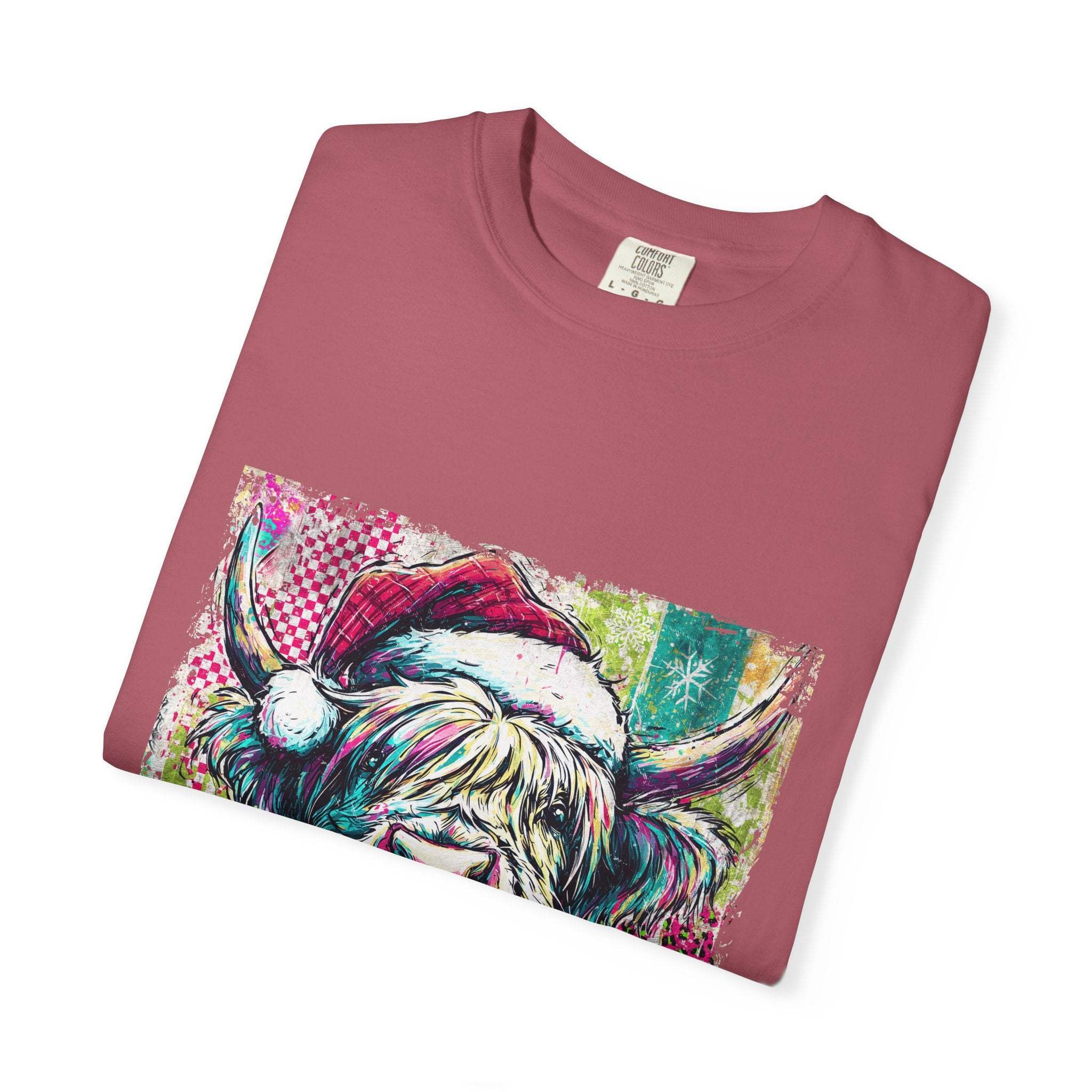 Folded retro Santa Highland Cow T-shirt in pink with colorful festive graphic design on front.