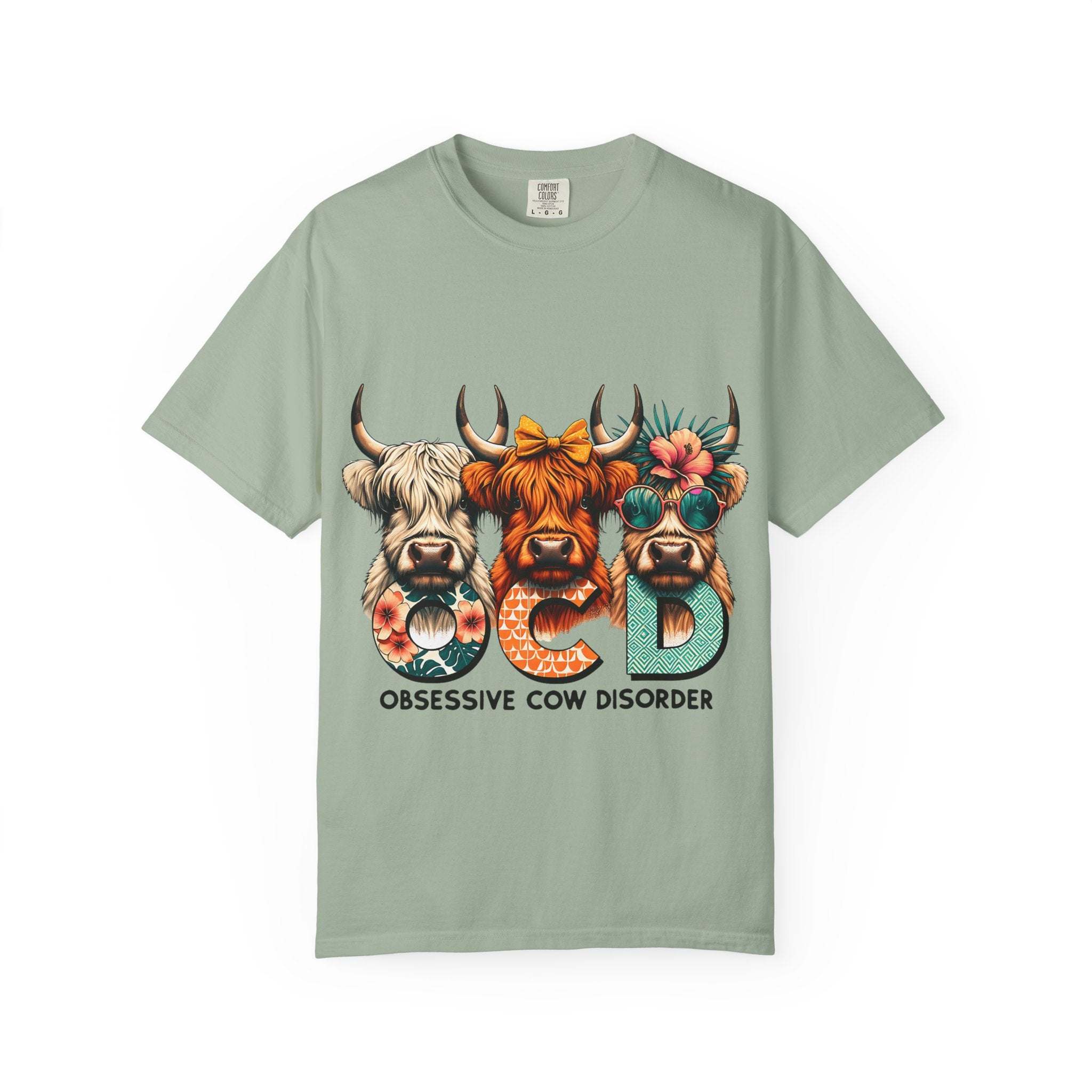 Funny OCD Obsessive Cow Disorder T-shirt with colorful cow faces and humorous text on a green garment-dyed fabric
