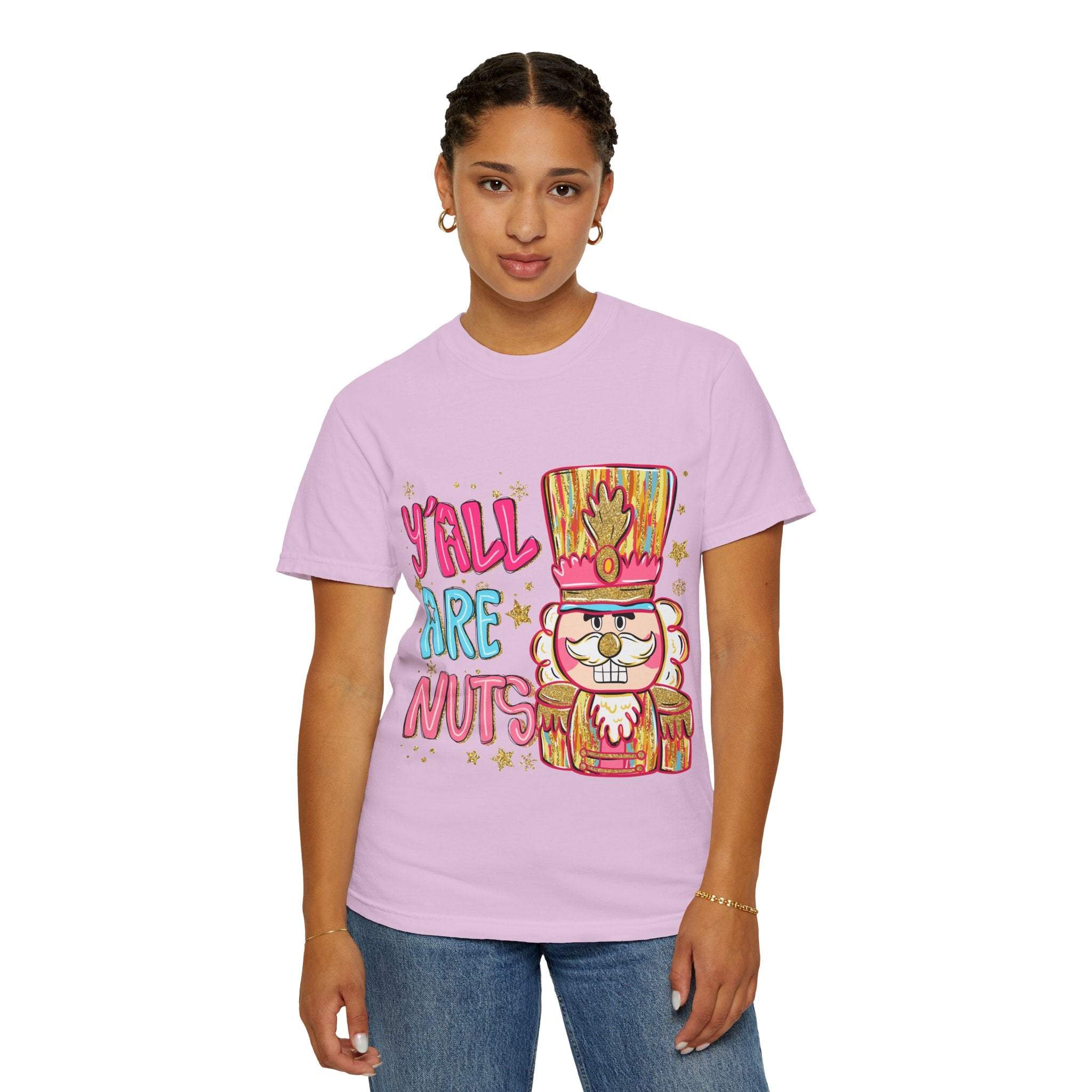 Woman wearing a pink Yall Are Nuts Nutcracker T-shirt with festive nutcracker graphic and text.