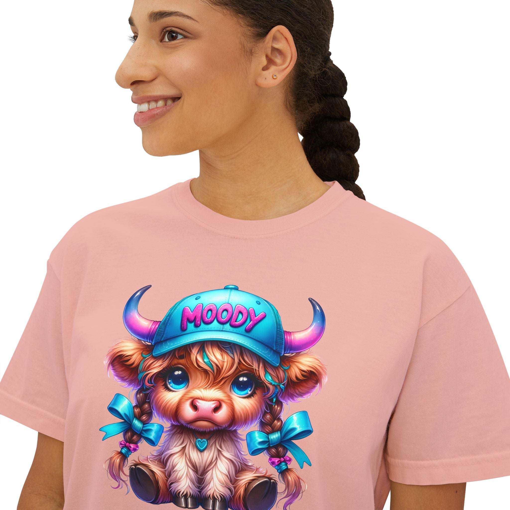 Woman wearing pink boxy tee with moody girl highland cow cartoon design on front