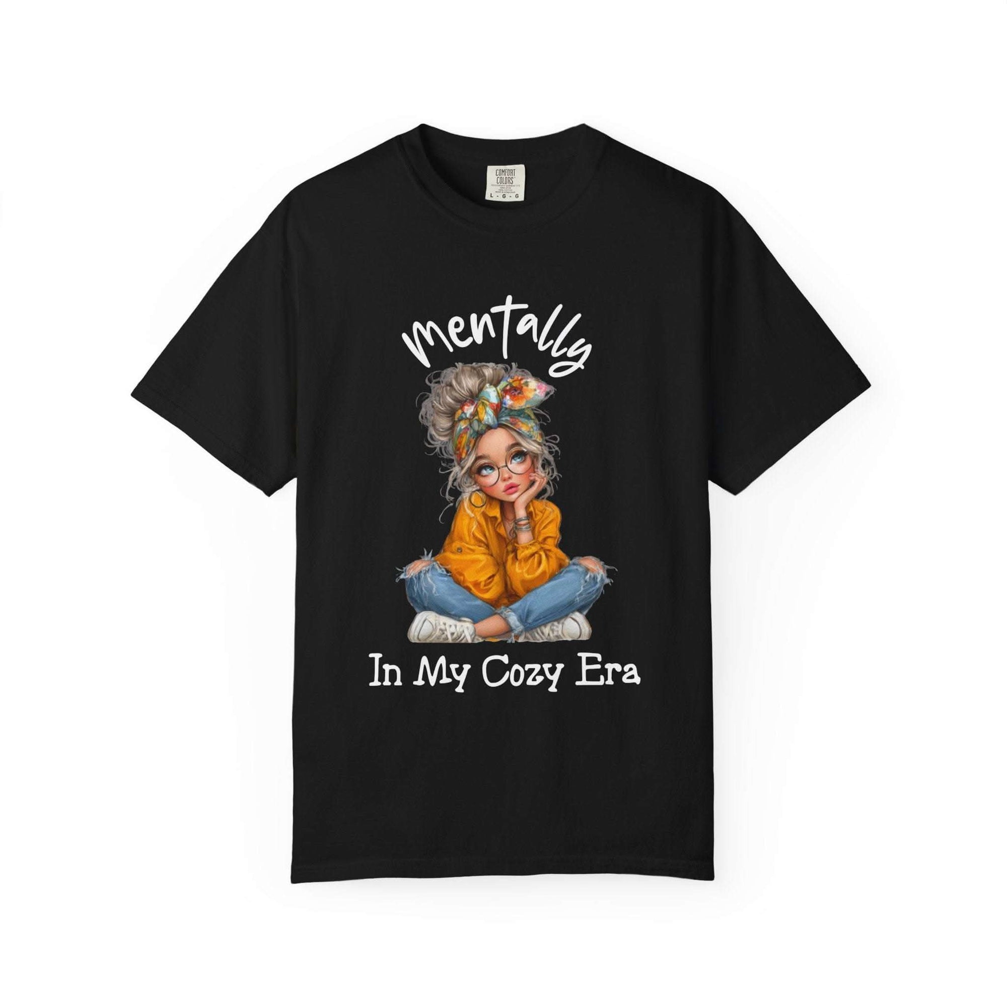 Black t-shirt with a graphic of a woman in an orange sweater and text 'mentally In My Cozy Era' on a white background