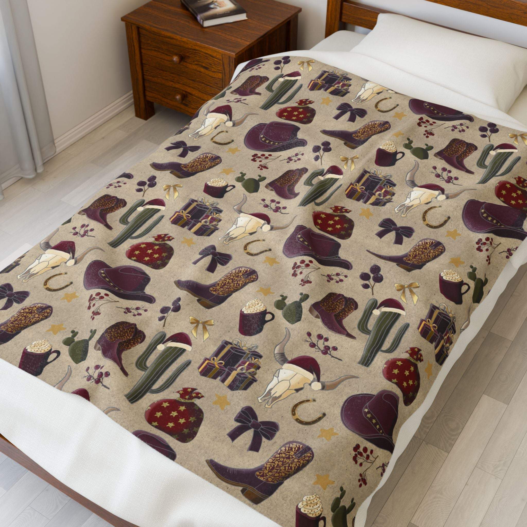 Plush blanket with cowboy Christmas design featuring boots, hats, cacti, and holiday elements on bed