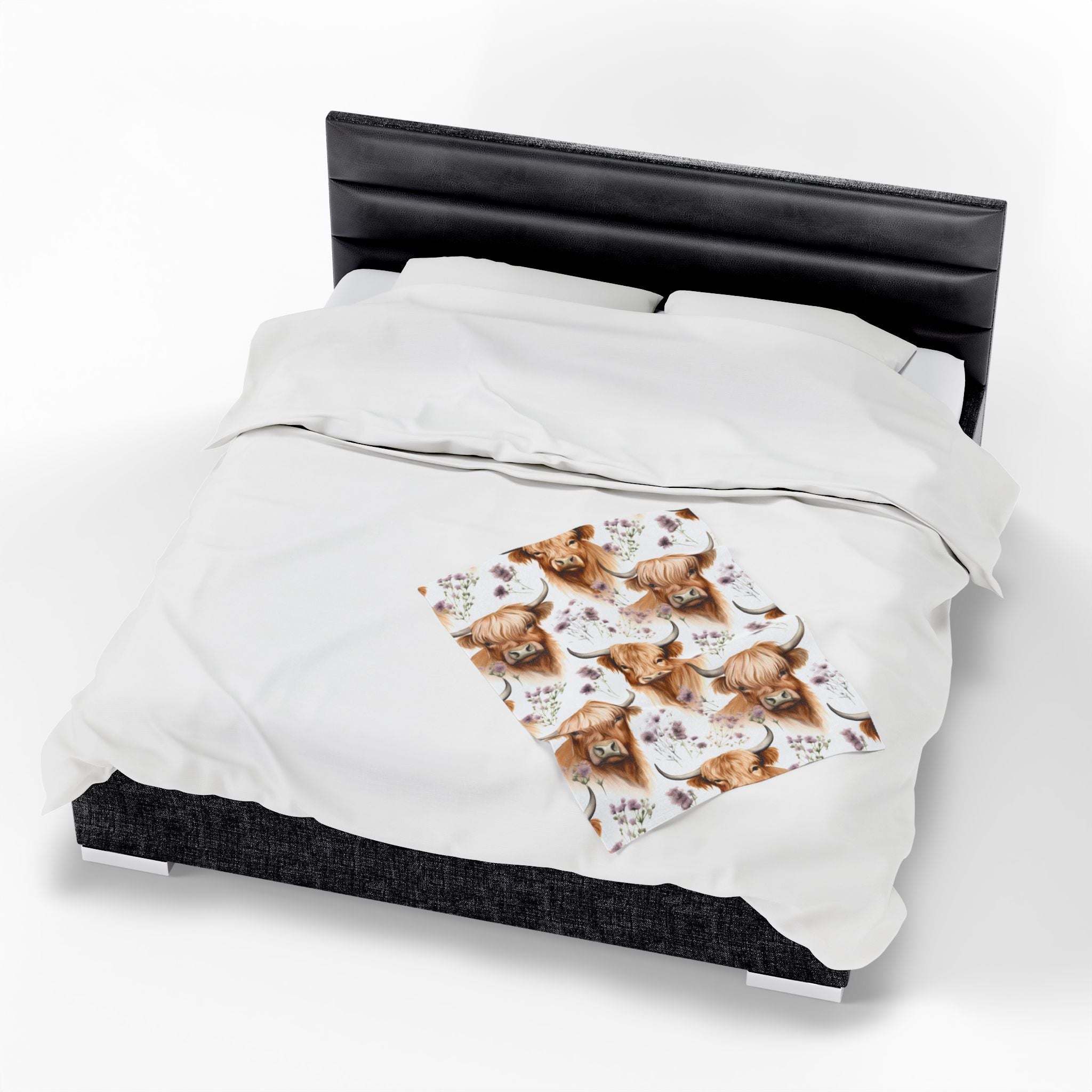 Velveteen plush blanket with floral Highland cow design on bed