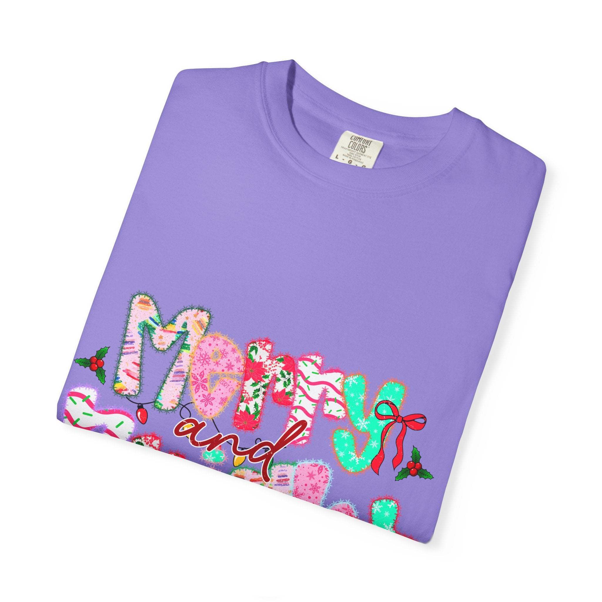 Folded purple Merry and Bright T-shirt with colorful holiday-themed text design