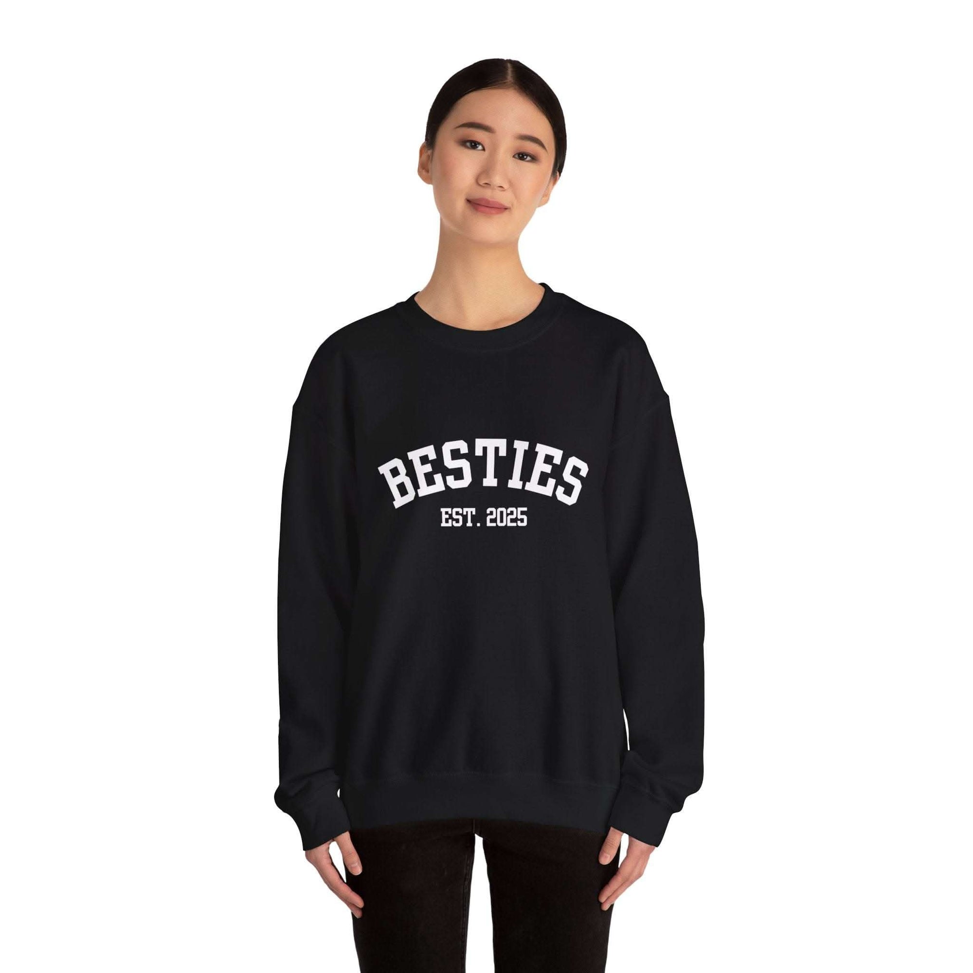 Person wearing a black sweatshirt with 'BESTIES EST. 2025' text on a white background