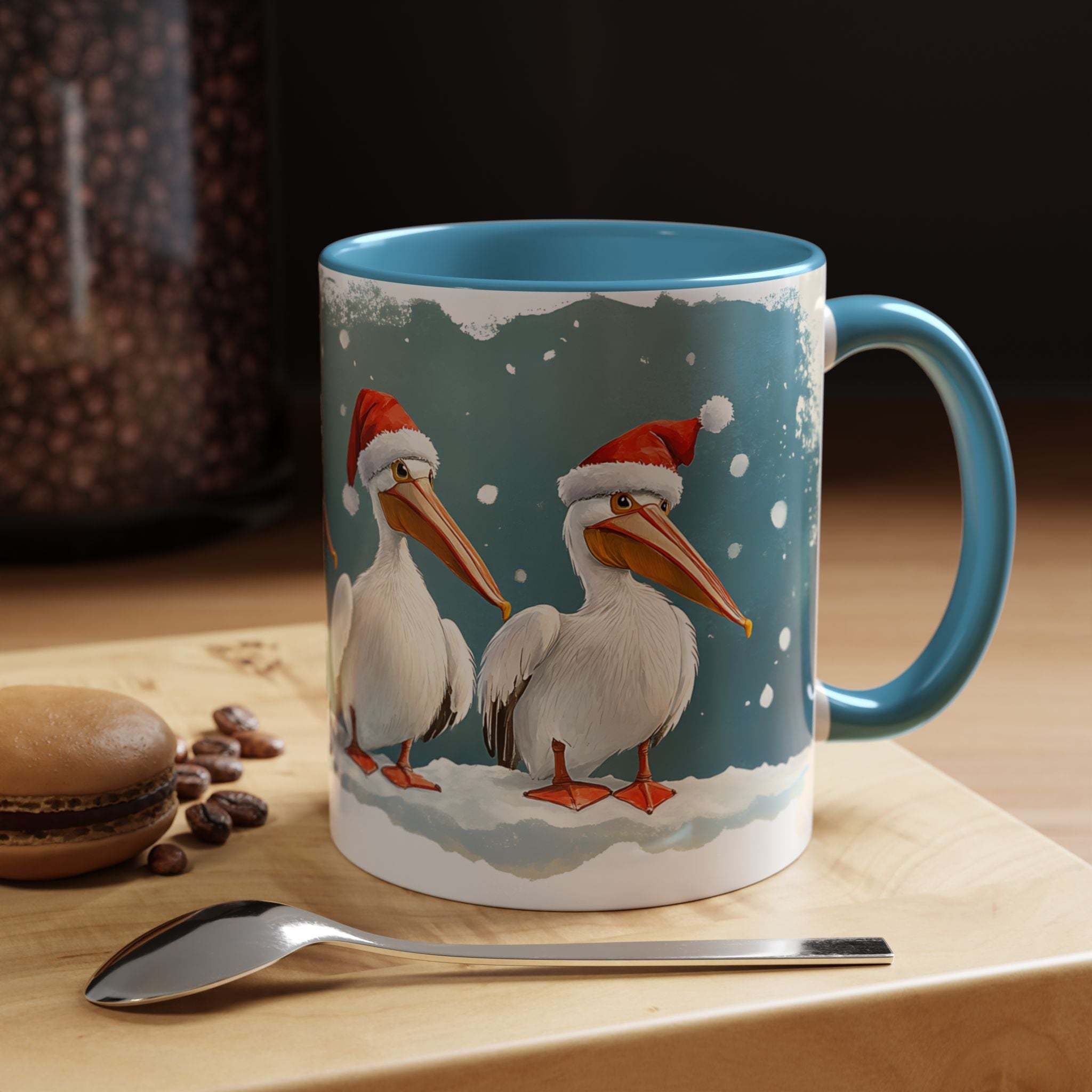 Mug with Christmas-themed design of pelicans wearing Santa hats on a wooden surface with coffee beans and a spoon.