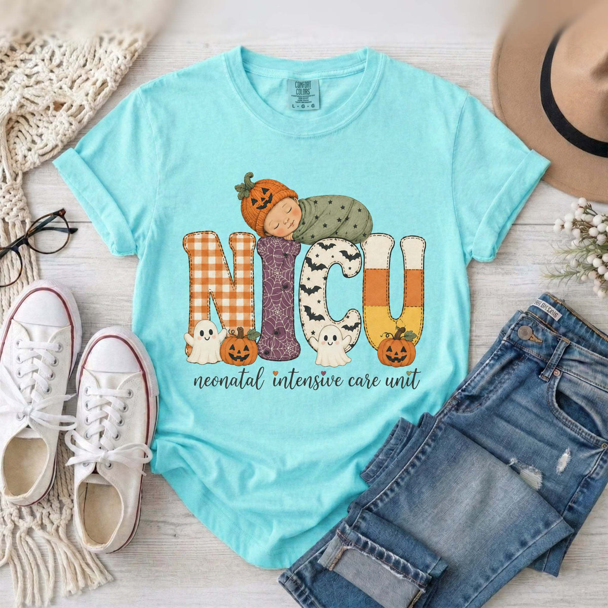 Chalky mint NICU nurse Halloween T-shirt with patchwork lettering, a sleeping baby in a pumpkin hat, ghosts, and jack-o’-lanterns.