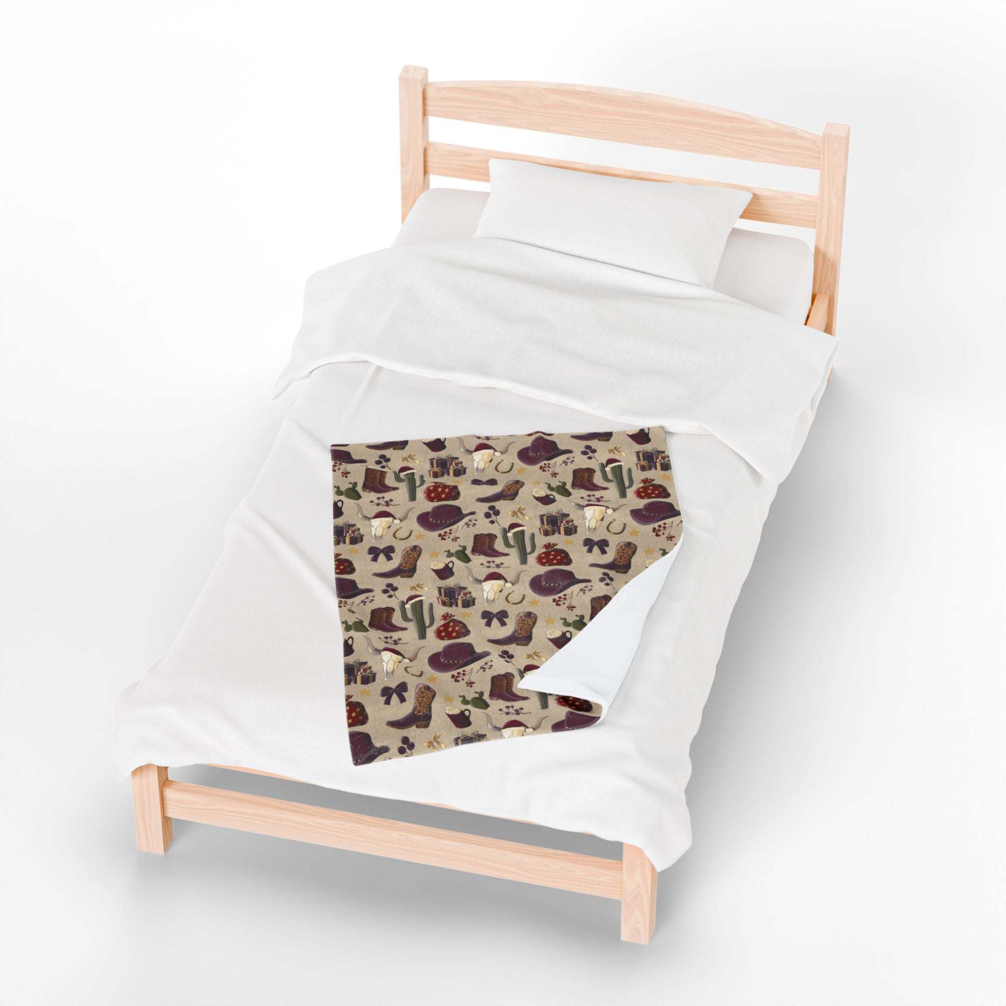 Cowboy Christmas plush blanket with festive western pattern on a wooden bed