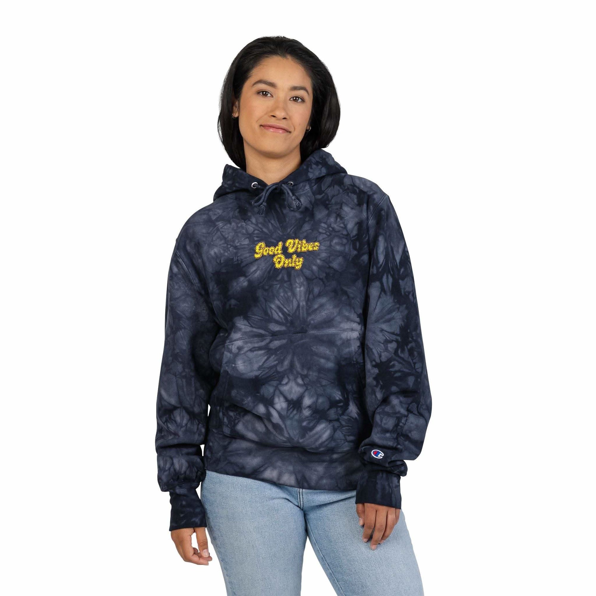 Woman wearing navy blue scrunch tie-dye hoodie with "Good Vibes Only" embroidered text and pouch pocket