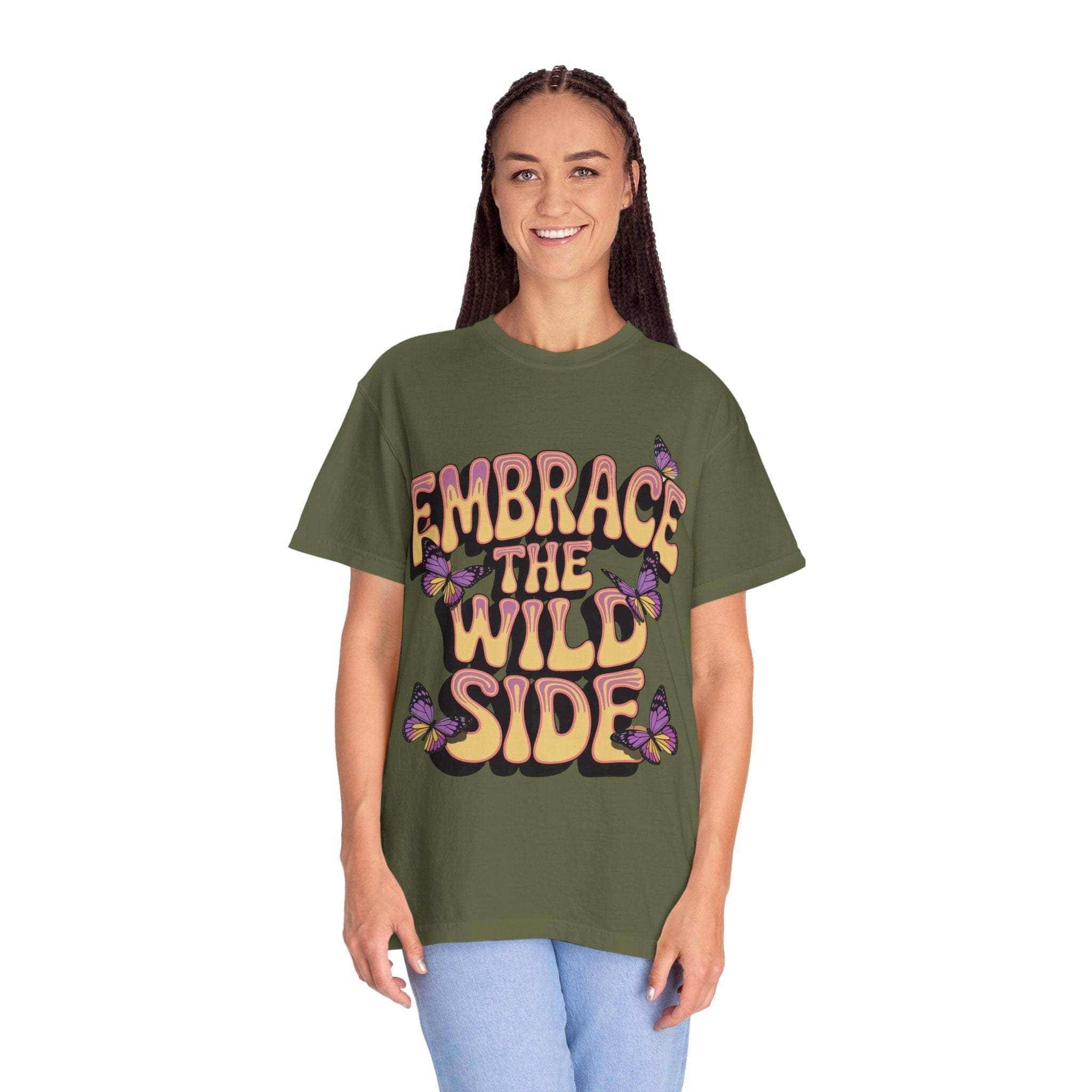 Olive green garment-dyed T-shirt with "Embrace the Wild Side" print and butterfly design, worn by a smiling model