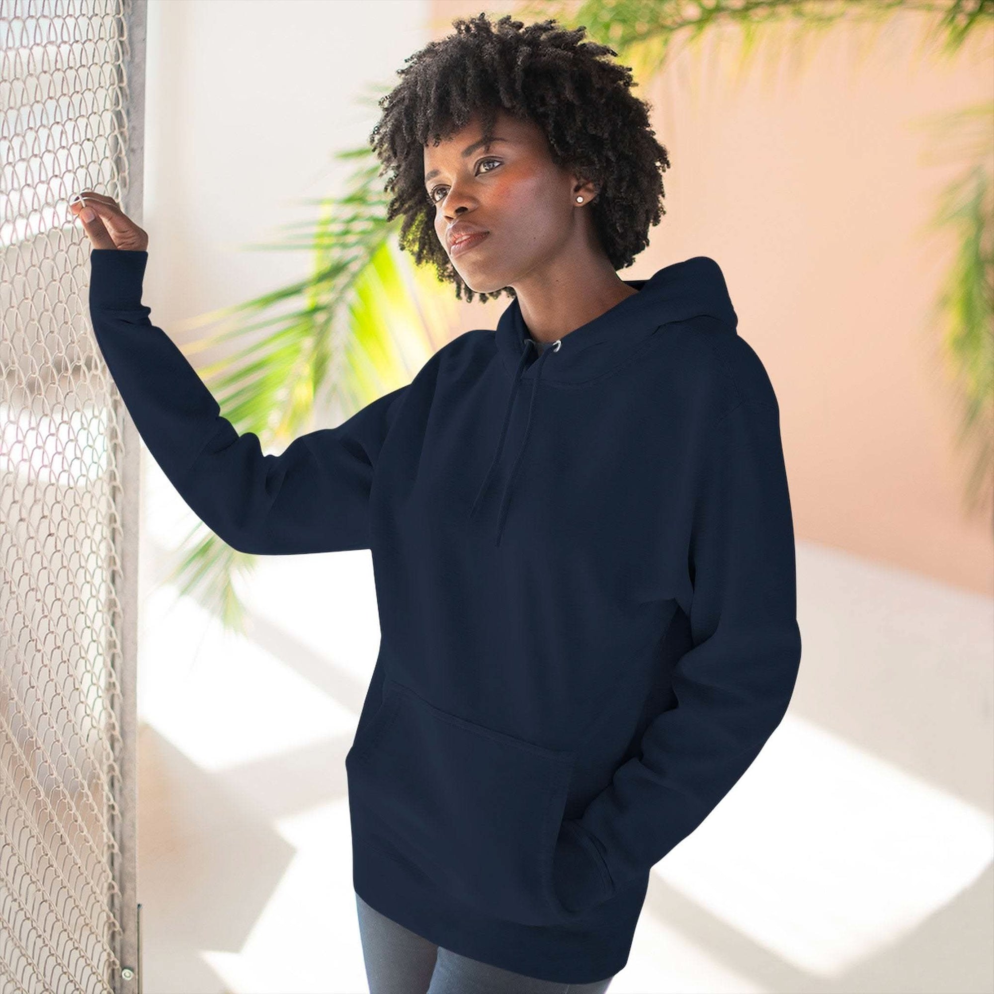 Woman wearing a navy blue fleece hoodie with adjustable hood and kangaroo pocket indoors