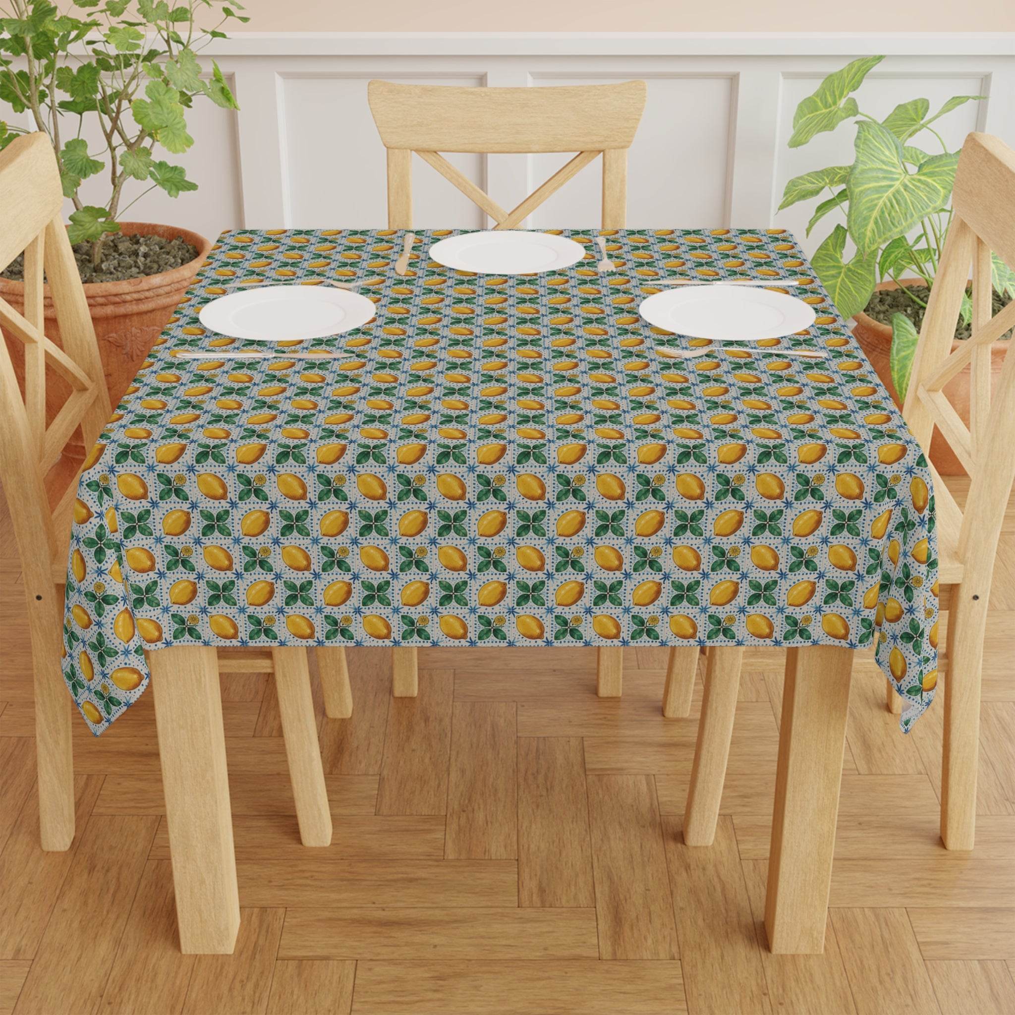 Mediterranean Lemon patterned tablecloth on wooden table with plates and chairs indoors