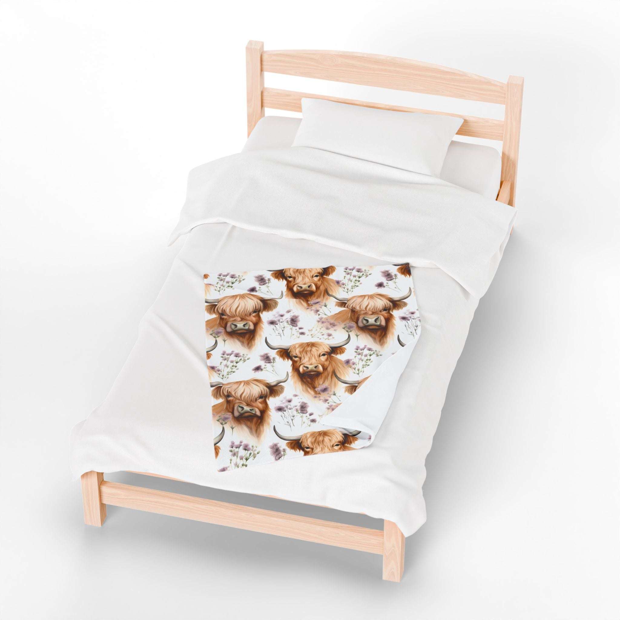 Plush blanket with floral highland cow design on bed, cozy and rustic velveteen fabric