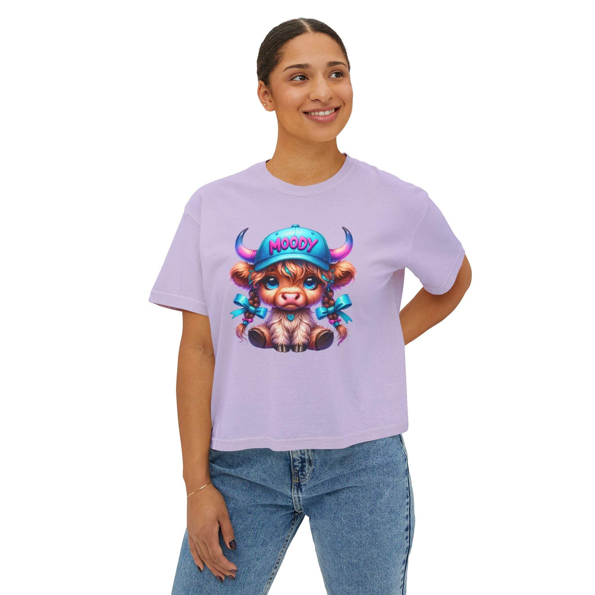 Woman wearing a lavender boxy tee with moody girl highland cow graphic and jeans