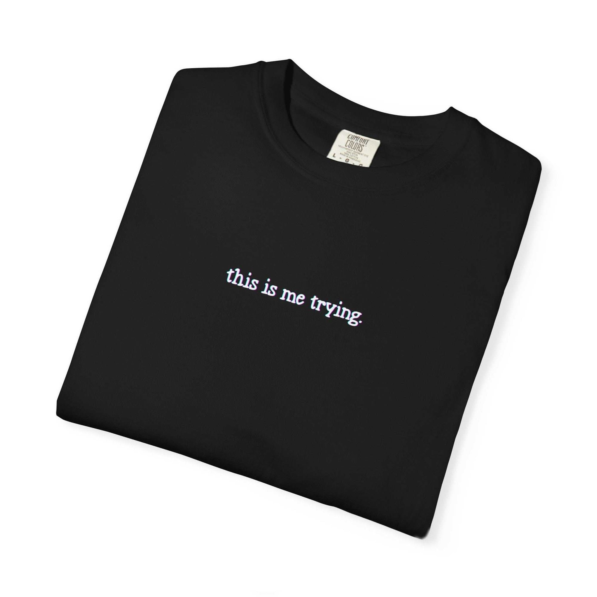 Black t-shirt with 'this is me trying' text on a white background