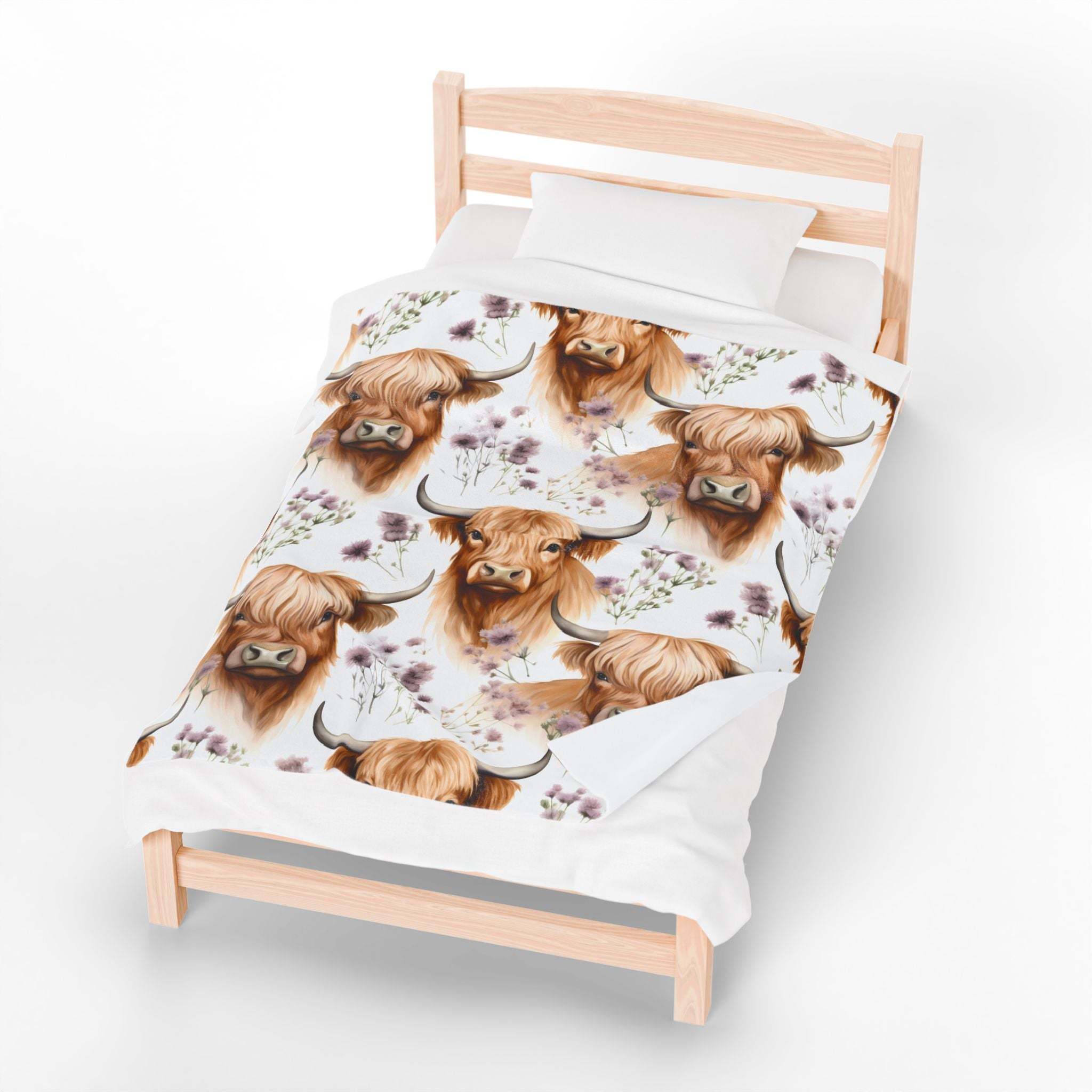 Plush blanket with floral Highland cow design on white bedspread
