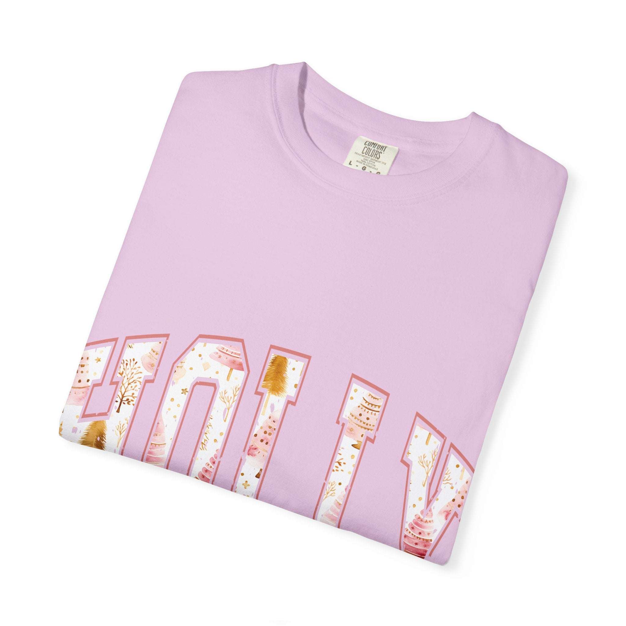 Folded pastel pink Varsity Holly Jolly T-shirt with festive holiday lettering on front