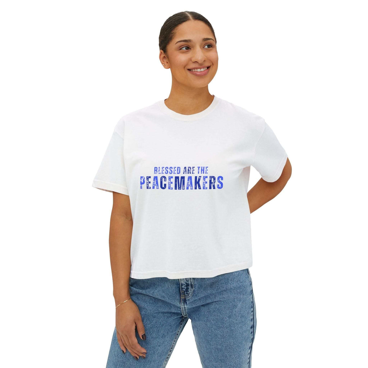 Woman wearing white Tee Blessed be the Peacemakers boxy shirt with blue text and casual jeans
