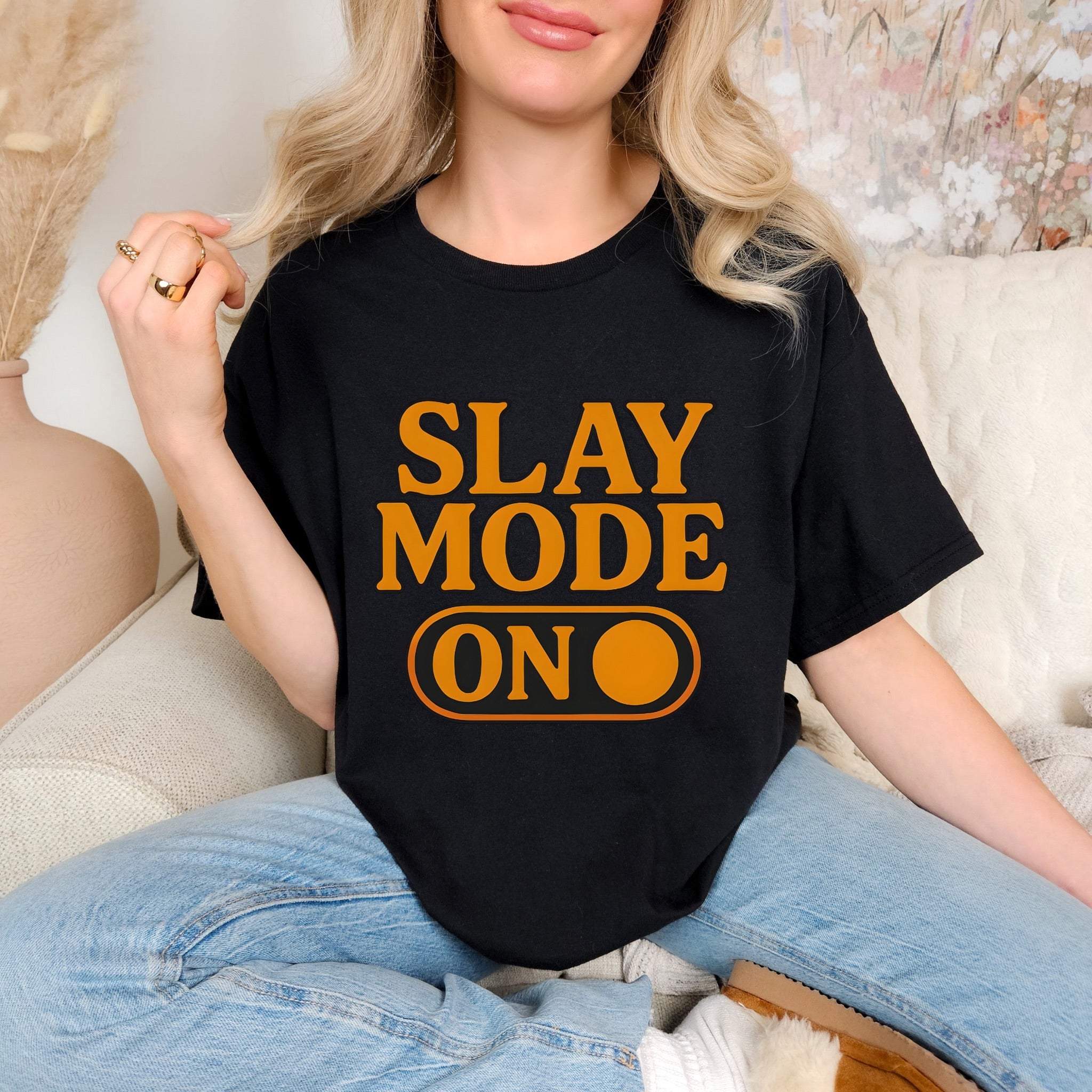 Black garment-dyed tee with bold orange "SLAY MODE ON" text, worn casually with jeans.
