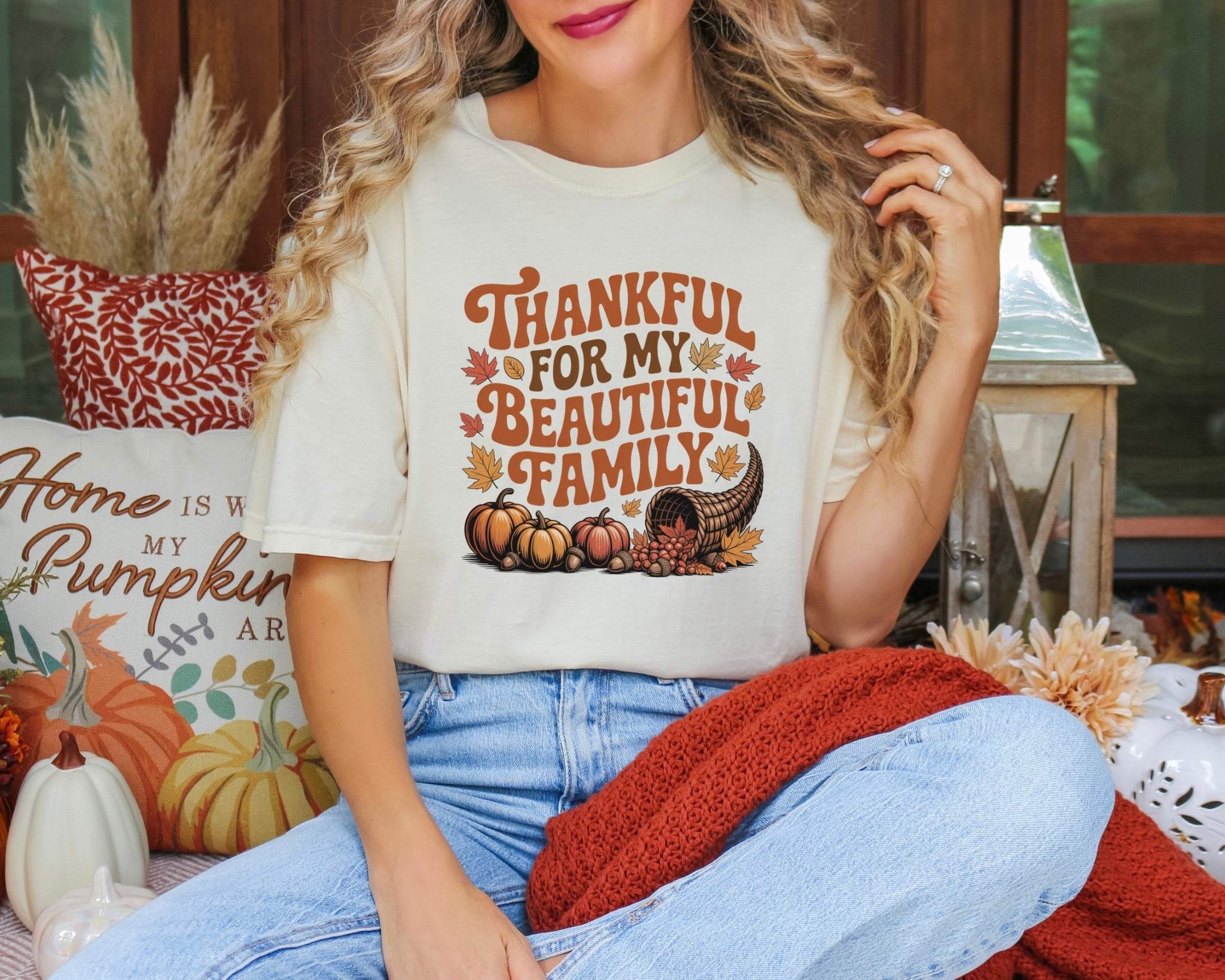 Woman wearing a cream unisex garment-dyed T-shirt with "Thankful for My Beautiful Family" fall-themed design featuring pumpkins and leaves