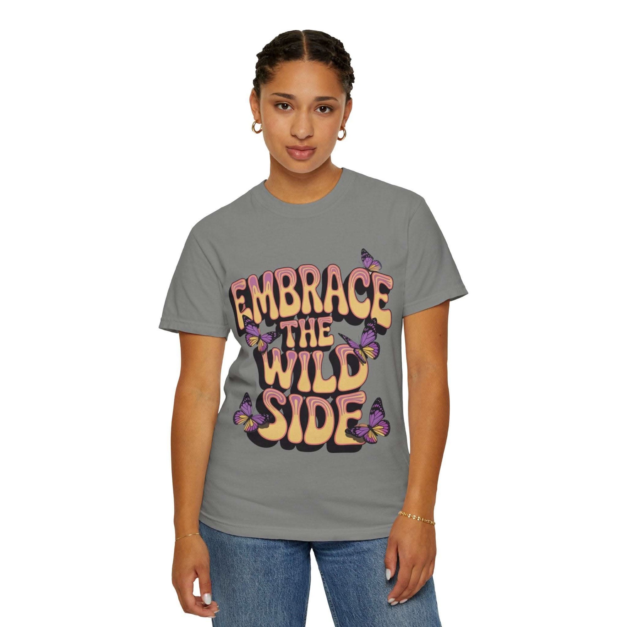 Garment-dyed T-shirt with "Embrace the Wild Side" print and butterflies on gray fabric worn by woman