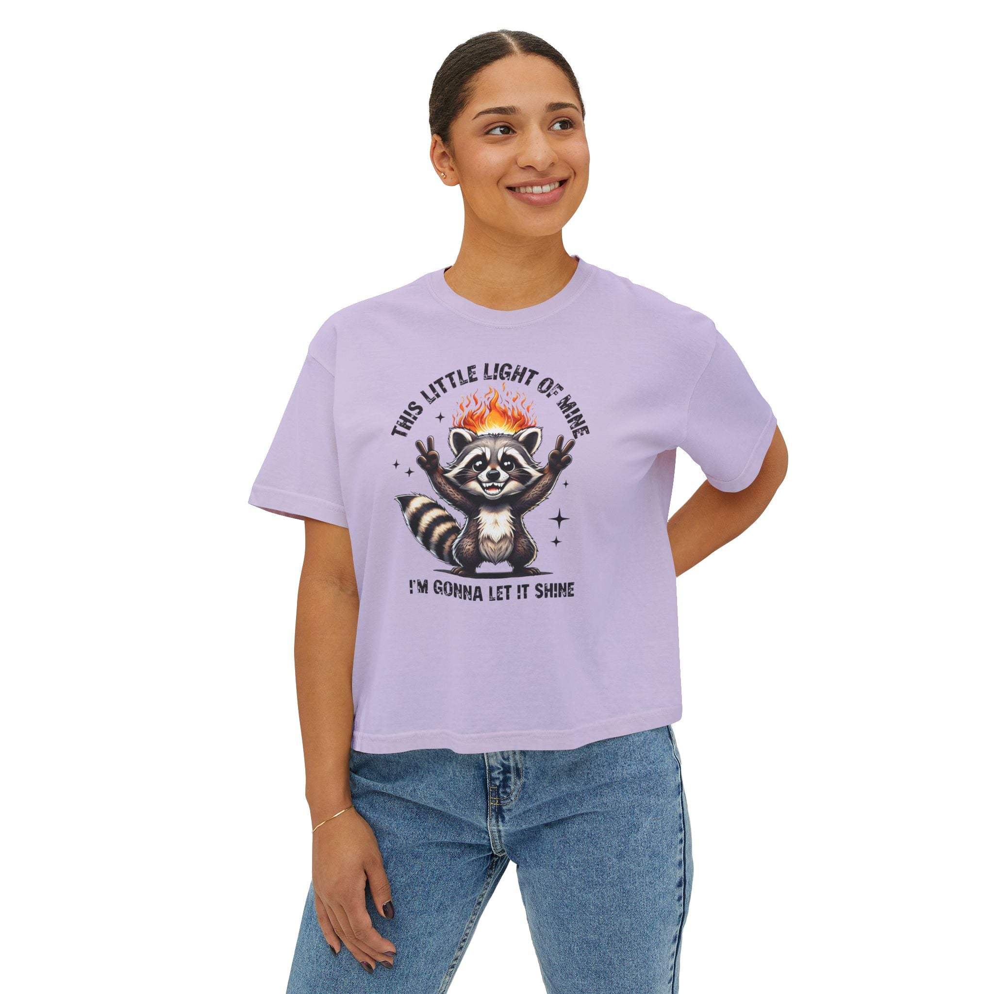 Person wearing a light purple t-shirt with a raccoon graphic and text on a white background
