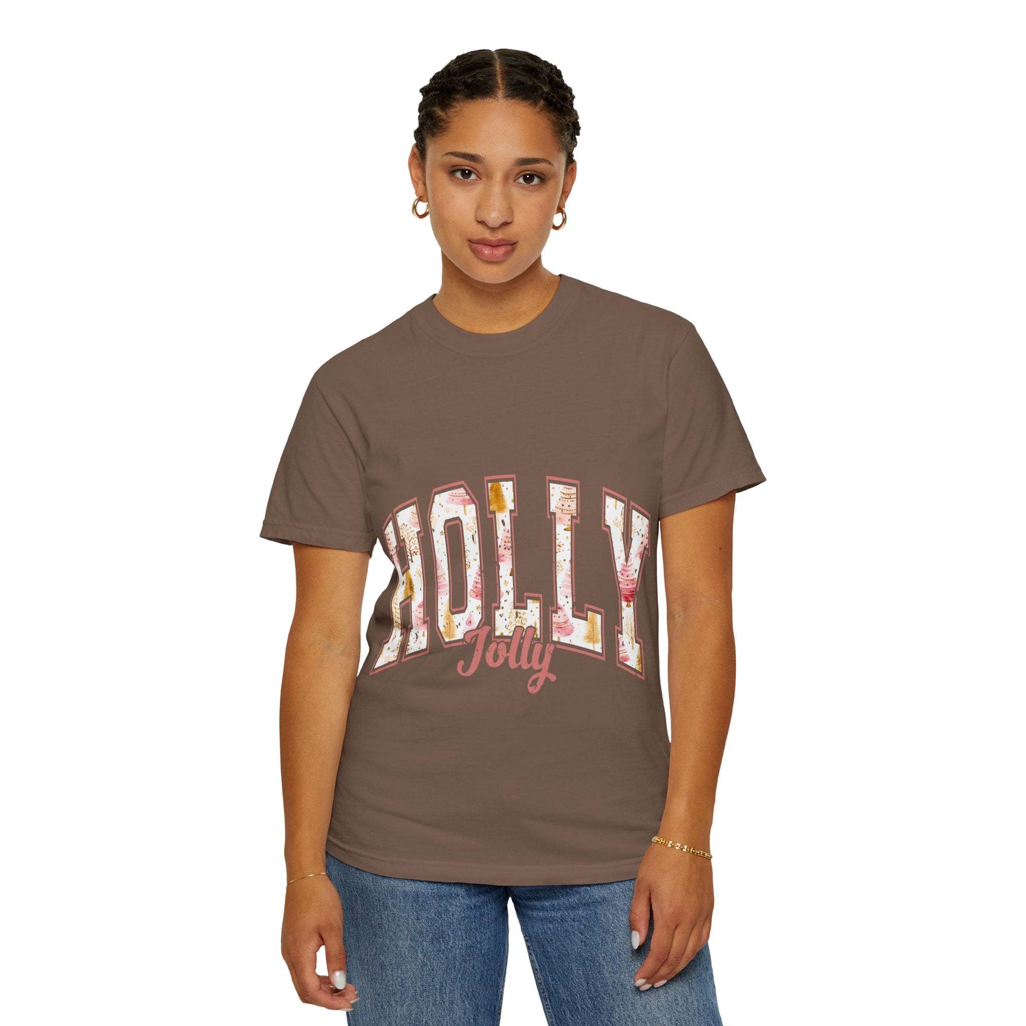 Woman wearing a brown Varsity Holly Jolly T-shirt with festive lettering, paired with blue jeans.