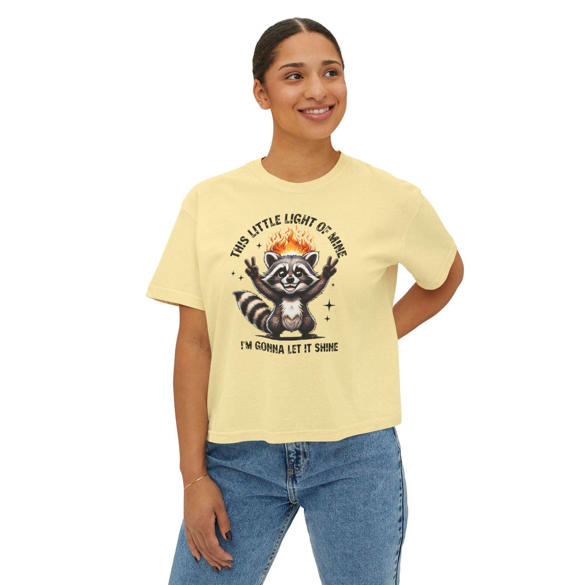 Woman wearing a yellow t-shirt with a raccoon graphic and text on a white background