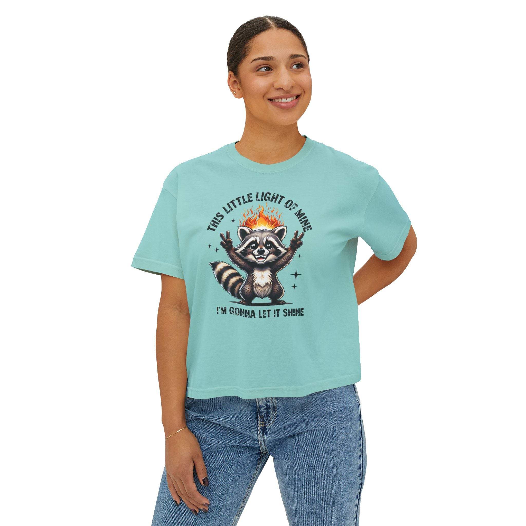 Person wearing a light blue t-shirt with a raccoon graphic and text on a white background